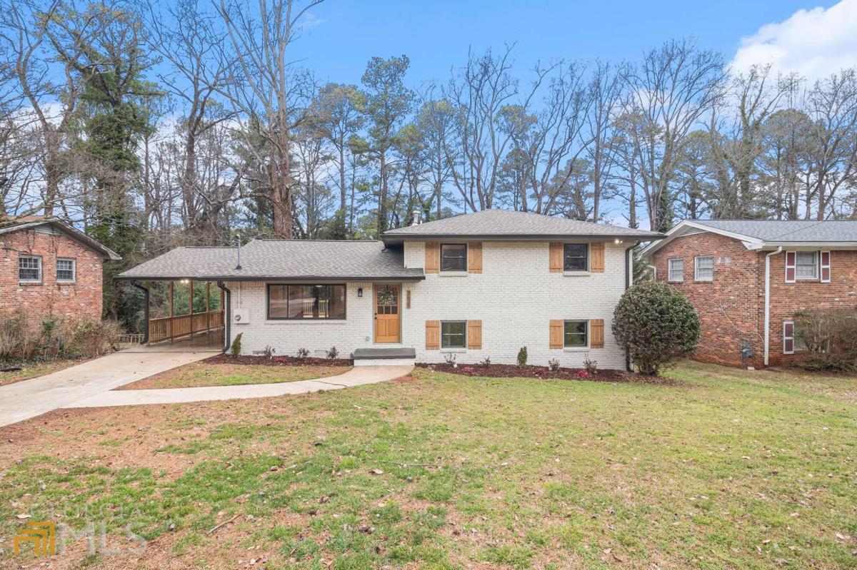 Gorgeous four-sided brick split-level has been completely renovated and reimagined! Walls were removed to create an open and entertaining floorplan between the kitchen, living room, and dining room. Fabulous high-end kitchen has all new soft-close cabinets with pantry, large island with seating for 4, quartz countertops, Whirlpool stainless steel appliance package, and tile backsplash. Massive primary suite on the lower level has enough space for a bedroom and sitting area with a decorative fireplace, giant walk-in closet, and an ensuite bath featuring a soaking tub, double sink vanity, quartz counters, walk-in shower with frameless glass, and linen closet. Two additional full baths have all-new tile, tubs, vanities, toilets, and fixtures. New and refinished real oak hardwoods throughout all levels. Large laundry room and plenty of storage throughout the home. The exterior features 2 brand new decks - one off the open living/dining/kitchen space on the main level, and one off the primary suite on the lower level. Full privacy fenced yard is ready for pets and family gatherings. Covered parking in the carport with driveway parking for at least 3 additional cars. Super convenient to I-285 and an easy walk to the local schools.
