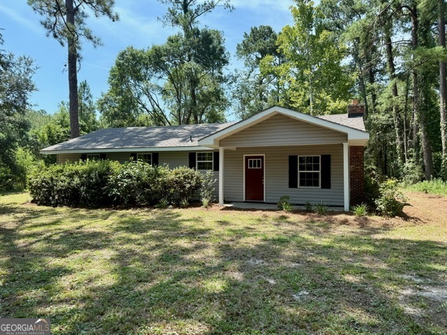 Step into rustic elegance with this beautifully updated 3-bedroom, 2-bath home nestled on a generous and private wooded lot. Home is conveniently located off of Hwy 67 just minutes away from I-16 great for a quick commute to and from work. From the moment you arrive, the inviting curb appeal, classic brick chimney, and bold red door set the tone for a home that perfectly blends character with modern upgrades. Inside, you'll be wowed by the dramatic vaulted ceilings with exposed beams and rich wood accents that create warmth and spaciousness throughout the open living and kitchen areas. A stunning floor-to-ceiling brick fireplace anchors the main living room, offering a cozy and stylish focal point. The fully renovated kitchen features stainless steel appliances, sleek marble-look countertops, a center island, and custom cabinetry that combines rustic wood finishes with crisp white for a fresh, balanced look. Just off the kitchen, enjoy a dedicated dining area with built-in cabinetry and a charming chandelier. Both bathrooms have been updated with modern fixtures and finishes, including updated countertops and sleek vanities. Durable luxury vinyl plank flooring flows throughout the home, combining beauty with easy maintenance. The home sits on a generous lot surrounded by mature trees, offering privacy, shade, and a peaceful, natural backdrop. Enjoy morning coffee or evening sunsets from the backyard patio, or explore gardening and outdoor entertaining in your spacious yard.