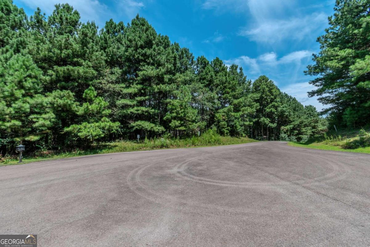 This 6.55-acre lot in the gated, all-paved road community of Sassafras Mountain has end-of-the-road privacy in a cul-de-sac, with a large amount of gentle wooded terrain (especially near the road access), and fairly mild slopes. In the northwest area of the lot is a small but audibly flowing stream. The community is about 15 miles away from Amicalola Falls State Park, whose namesake waterfall is over 700 feet high, and which also includes beautiful hiking trails, an inviting and helpful visitor's center, and offers programs for archery and axe throwing, guided hiking tours, and zipline canopy tours. The lot itself is less than 5 miles away from popular area attractions such as Cartecay Vineyard and Reece Orchards. This property offers the privacy and peacefulness of the North Georgia country life, but still close to the modern conveniences and amenities of the city of Ellijay, so visit the property today and start planning your new home!
