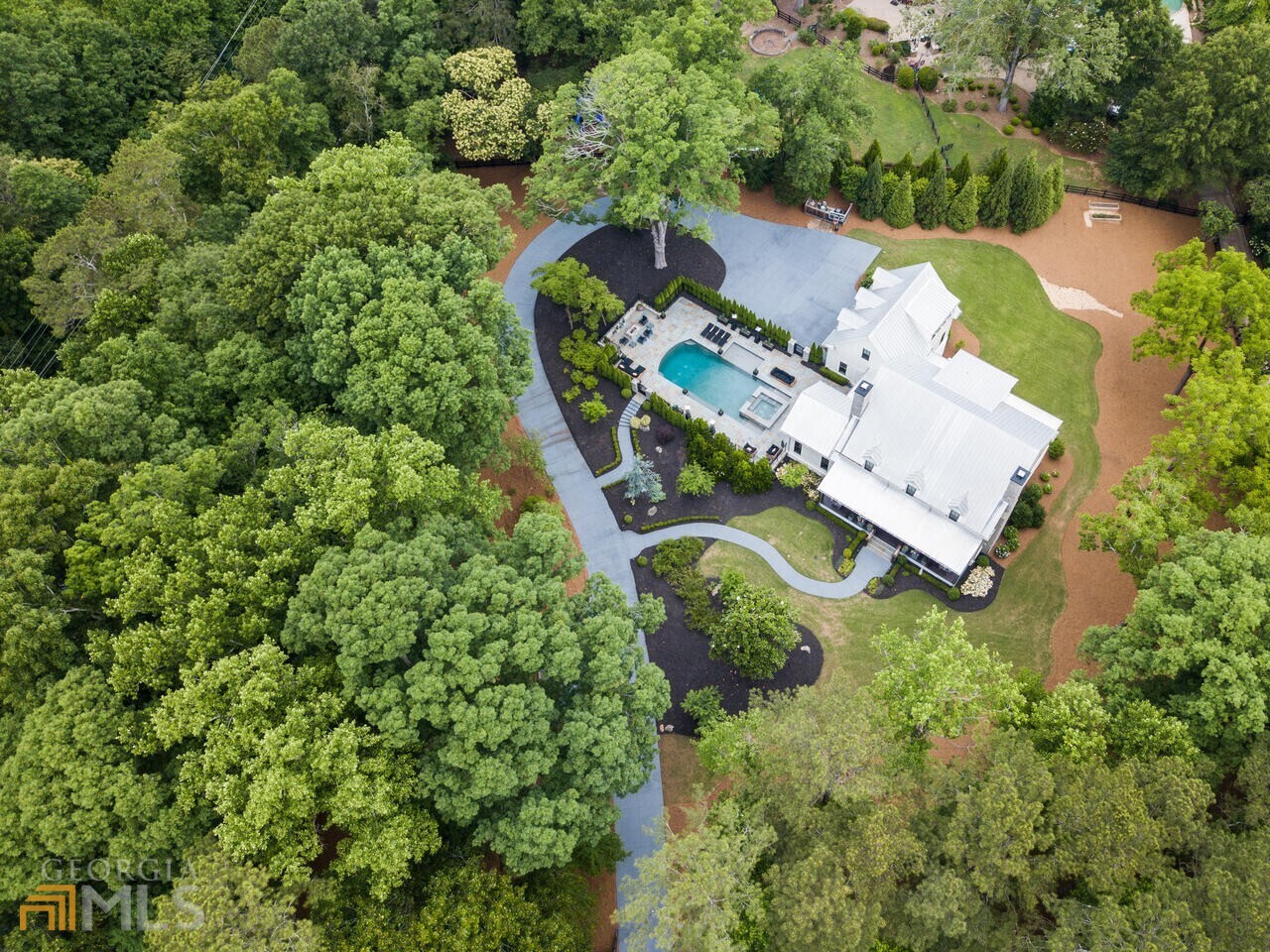 Gated modern custom farmhouse built by Steve Powell Homes. Located minutes from downtown Alpharetta, Avalon and highway GA 400. Home is overlooking 100 year old whispering oak trees and sits beautifully on 2.45 +/-acres. Large front porch with cedar beams featuring tongue and groove ceiling, two porch swings. Walk out from your first floor through Lanai Bi-folding glass doors that lead to an amazing heated pool, with spa and accent waterfall. Full pool Bath and Fire Pit makes entertaining outdoors effortless. 12 foot ceilings on Main Level, Open Floor plan invites you into the Chefs kitchen with rustic beams ceiling, high-end appliance package, large island with farm sink, quartzite countertops, and custom built vent hood. Pennsylvania Barn wood Hardwood flooring throughout. Beautiful windows on the main floor bring in loads of natural light. Exquisite design selections throughout the home including tile, light fixtures, and hardware. Owners suite on Main Level with spa like bath with heated floors, large his and hers closet with island, custom built-ins. Wonderful laundry/mud room with two washers and two dryers, sink and tons of storage. Large secondary bedrooms upstairs with private baths and great walk-in closets featuring custom built-ins. Cozy study nook. Terrace Level features; bedroom with full bath, workout room, home theater, boat/car garage/workshop with great storage space with built-ins. Beautiful winding driveway with additional parking pads for entertaining, generator, Control 4 Home automation that controls lighting, HVAC and security system.