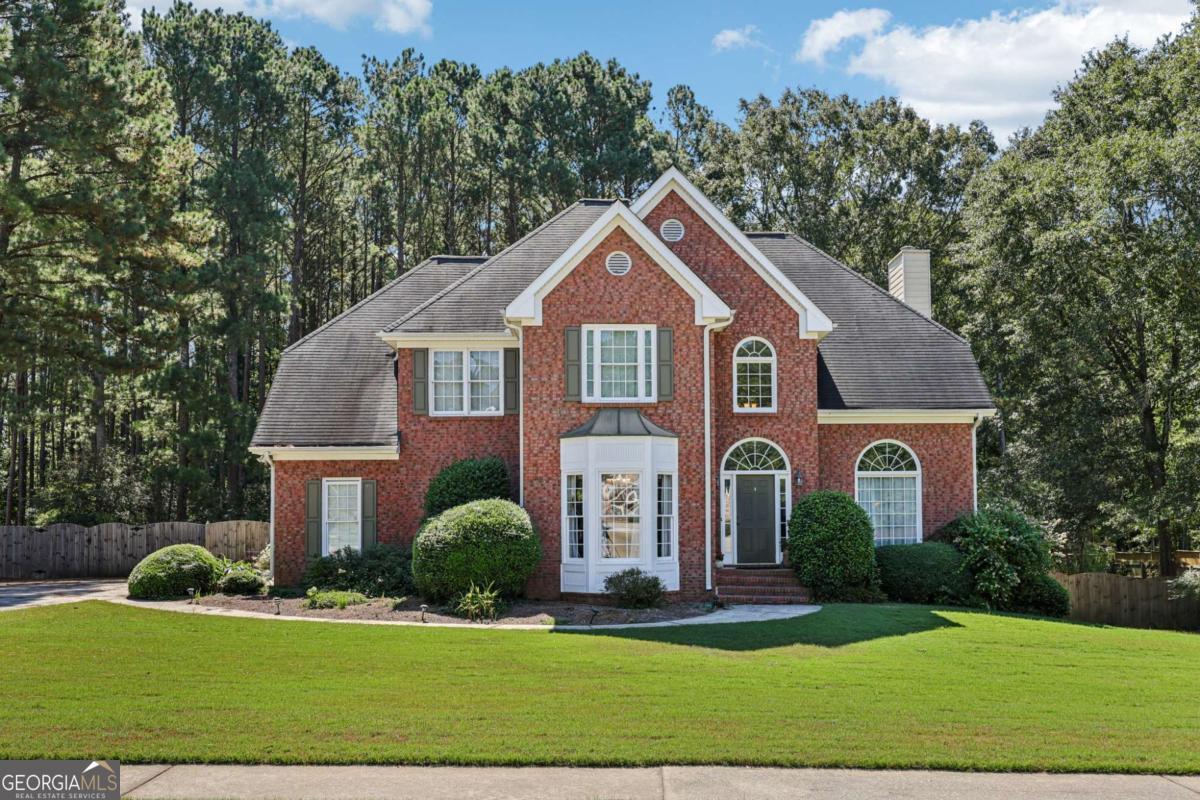 Spacious home on nearly an acre! Feel welcomed with a sweeping front lawn and mature landscaping. Step inside to find gorgeous hardwood floors flowing through the two-story entry and into the formal dining room. A versatile front flex room with built-ins is ideal as a formal living room or private office. The light-filled living room features built-ins and a cozy fireplace, opening seamlessly to the kitchen with a breakfast bar, granite counters, tile backsplash, wood floors, stainless steel appliances, butler's pantry, and a charming bay-window breakfast nook. A convenient laundry room and half bath complete the main level. Upstairs, retreat to the oversized primary suite with a sitting area perfect for reading or movie nights. The spacious en-suite bath offers dual sinks, a soaking tub, separate shower, and a large walk-in closet. Three spacious secondary bedrooms and a full bath provide plenty of room for everyone! The finished basement includes a large flex room-perfect for a game room, media room, playroom, or hobby space-along with a full bathroom with dual showerheads and generous unfinished storage. Step outside to your private outdoor oasis: a fenced yard backing to woods, plus a two-level deck with a pergola-covered seating area above, a lower deck designed for grilling and entertaining, and a covered space with a patio slab. Don't miss your opportunity to tour this home today!