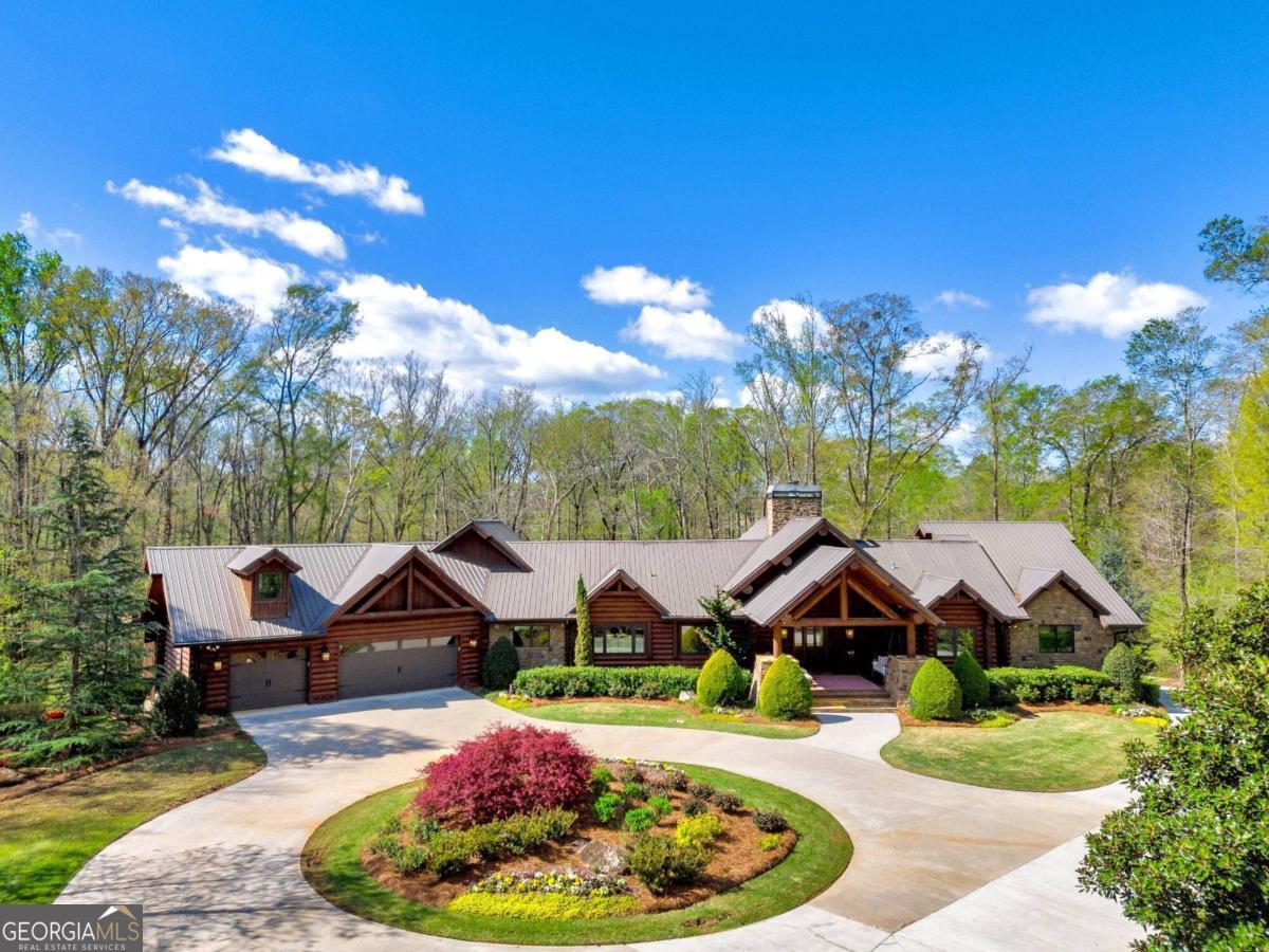 Welcome to your dream country estate nestled alongside the serene North Oconee River! This remarkable property boasts 11.95 acres of picturesque land, offering a perfect blend of luxury living and natural beauty. As you enter through the gated entrance, you're greeted by the charm of wood log and stone construction, creating a rustic yet elegant atmosphere. The main residence features 6 bedrooms and 4 full bathrooms, along with 2 convenient half baths, providing ample space for family and guests. Step inside to discover a meticulously designed interior, highlighted by a spacious owner suite on the main level, complete with a huge custom walk-in closet and a private screened porch overlooking the tranquil surroundings. The gourmet kitchen is a chef's delight, equipped with beautiful Viking appliances and granite countertops, perfect for preparing delicious meals and entertaining guests. Full water filtration system with reverse osmosis. Venture downstairs to the finished terrace level, where luxury meets leisure. Here, you'll find a fully equipped gym, ideal for staying active and healthy, as well as a private safe room for added security and peace of mind. Step outside to the heated saltwater pool, surrounded by professional landscaping, creating a serene oasis for relaxation and enjoyment. For added convenience, the terrace level also features its own separate entrance, complete with a kitchen and laundry room, providing flexibility and privacy for guests or extended family members. Additionally, the property includes an inviting in-law suite over the garage, offering comfortable accommodations for loved ones. A highlight of the estate is the impressive 68x90 man cave/shop building, complete with living quarters, a full bathroom, a screened porch, and a laundry room, as well as power garage doors designed to accommodate a motor home or other large vehicles. Providing ample space for hobbies, storage, or creative endeavors. Whether you're a car enthusiast, woodworker, or artist, this versatile space offers endless possibilities. Situated just minutes away from I-85, HWY 441, Downtown Commerce, and Downtown Jefferson, this exceptional property offers the perfect balance of tranquility and accessibility. Experience the ultimate in country estate living, where every detail has been thoughtfully crafted to exceed your expectations. Welcome home!
