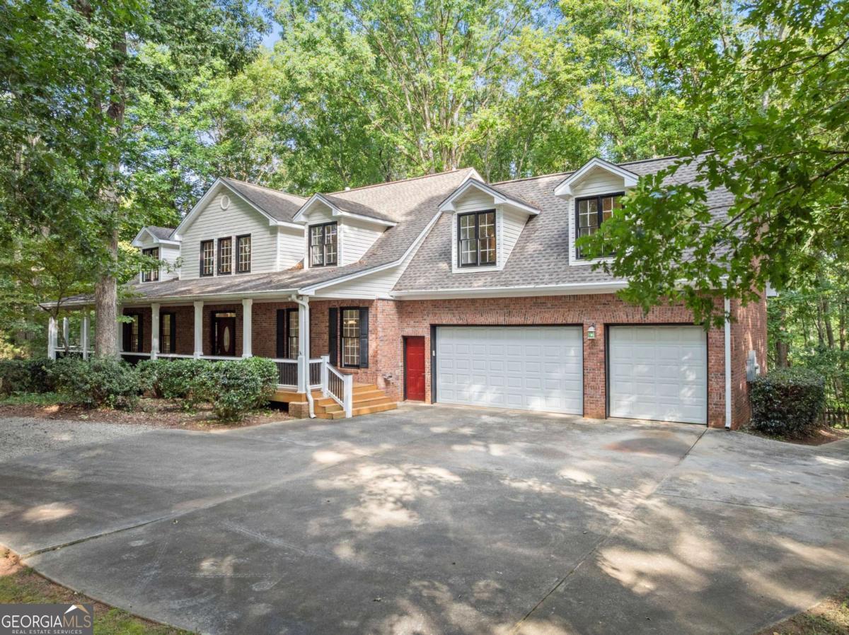 Private 2.08-acre retreat with finished basement and 3-car garage. Set on a wooded lot, this home offers the perfect balance of privacy, functionality, and space across three finished levels. From the oversized covered front porch, step into the two-story foyer that opens to a layout filled with windows and natural light. The main level features a primary suite with dual walk-in closets and a spacious bath, along with a secondary bedroom and half bath. At the center of the home is the two-story living room with fireplace, showcasing walls of windows and glass doors that open to the expansive back deck with both covered and uncovered areas, perfect for entertaining or relaxing while overlooking the wooded property. The separate dining room is located just off the foyer, while the great room flows into the breakfast area and kitchen, which offers granite countertops, wood cabinetry, and a wall oven with built-in microwave. Dual staircases lead upstairs to two large bedrooms, each with a private bath, along with a spacious recreation room ideal for hobbies, play, or a media lounge. The finished basement extends the living space with a recreation/game room, office/flex room, bedroom, full bathroom, and a large workshop, plus walk-out access to a covered patio. Additional highlights include a 3-car garage, multiple outdoor living spaces, a separate storage shed, and wooded views from nearly every room; an exceptional opportunity to enjoy a private retreat while staying close to conveniences.