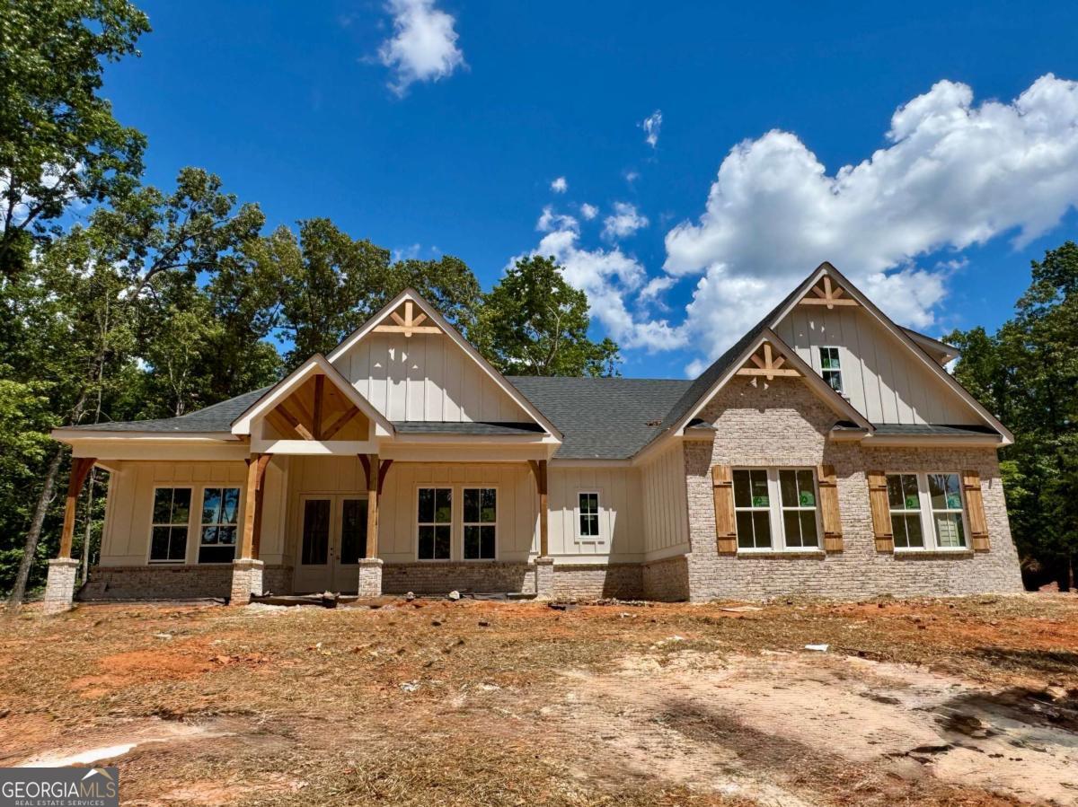 Welcome to 123 Stillwater Lane in Dawsonville, Georgia - a brand-new custom ranch-style estate nestled on over 3.3 private acres in an exclusive gated community, with completion anticipated by September. A long, winding driveway leads to this stunning home perched on a gentle hilltop, offering a perfect blend of luxury, functionality, and serene countryside living. Designed with both beauty and comfort in mind, this spacious home features 5 bedrooms and 4.5 baths, including four bedrooms on the main level and a private upstairs suite with its own full bath - ideal for guests or multigenerational living. Step inside to find durable and elegant LVP flooring throughout, designer tile selections in each bath, and breathtaking Taj Mahal quartzite countertops in the chef's kitchen. The kitchen is a showstopper, complete with a massive walk-in pantry that includes custom cabinetry and a built-in beverage fridge - perfect for entertaining or everyday ease. The open-concept living area showcases vaulted ceilings and a brick fireplace, setting the stage for cozy gatherings. Rich architectural details abound, including tongue-and-groove wood ceilings on both the front and rear porches, accented by cedar columns and decorative corbels, plus refined custom trimwork throughout the home - from the mud bench to the built-ins. The expansive laundry room, thoughtfully located off the master closet, offers exceptional storage and custom cabinetry, making it as beautiful as it is functional. Outside, the home's grey flagstone porches create inviting outdoor living spaces where you can enjoy the peace and privacy of your surroundings. The oversized three-car garage provides ample space for large vehicles, recreational toys, or even a workshop. 123 Stillwater Lane is more than just a home - it's a private retreat designed for those who appreciate craftsmanship, space, and quiet luxury. Don't miss your opportunity to own this one-of-a-kind property before construction is complete.