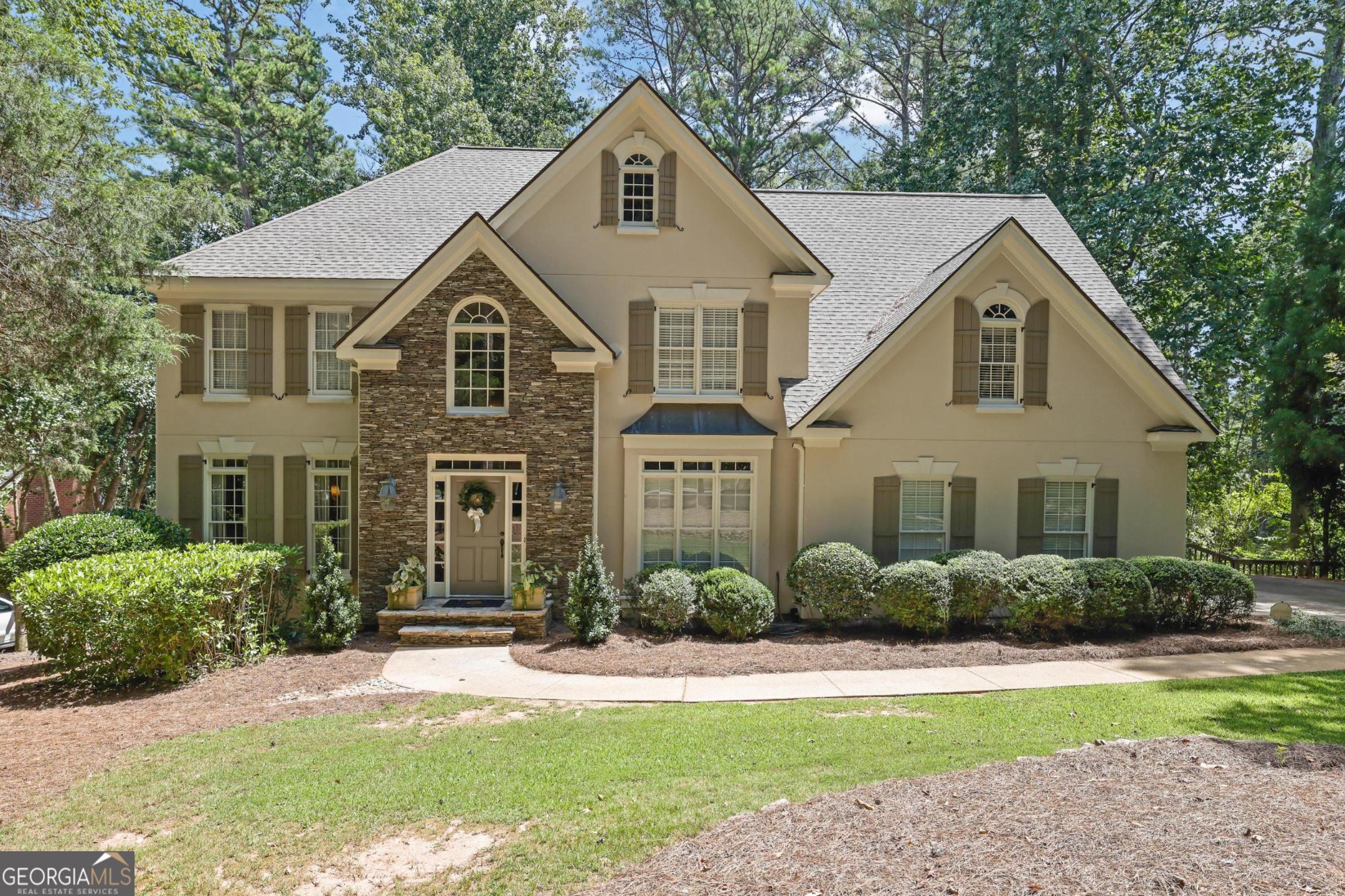 Nestled in Milton's coveted Wood Valley subdivision, this beautifully updated home blends timeless elegance with modern comfort. With no annual HOA, top-rated schools, and direct access to the upcoming Milton City Park & Preserve, the location is truly unmatched. The newly renovated kitchen is the heart of the home, featuring custom cabinetry, quartz counters, stainless appliances, and a large island that flows seamlessly into the great room. Step outside to an extended covered deck with fireplace-perfect setting for cozy evenings, lively gatherings, or game day under the stars. A dramatic two-story foyer and guest suite on the main level add both style and function. Upstairs, a serene primary suite is complemented by three spacious bedrooms with private baths. The finished daylight basement offers a fireplace, wet bar, bedroom, full bath, and generous closet space-ideal for guests or gatherings. With recent updates including a new roof and water heater, this move-in-ready residence is a rare opportunity in one of Milton's most desirable settings.