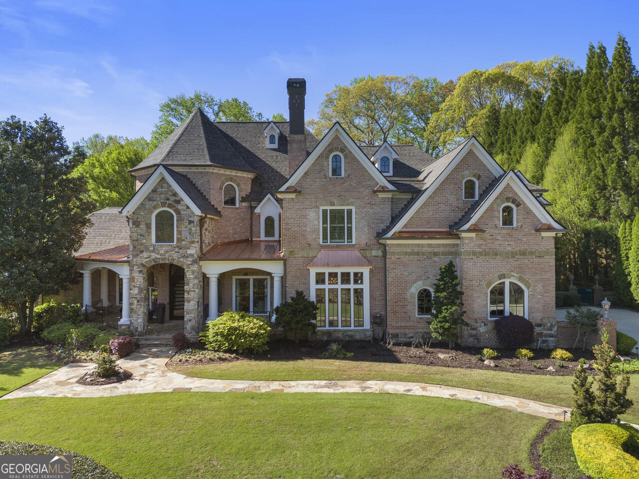 This magnificent estate located in prestigious Manor Golf and Country Club offers unparalleled luxury and 2.5 acres of unprecedented recreation and relaxation. The home and grounds offer you the lifestyle that up until now you only dreamed of. It's your own personal Field of Dreams come true! The scrumptious interior has been renovated with impeccable attention to detail throughout in the style of casual elegance. You will savor the exquisite designer lighting and special touches throughout. The completely remodeled designer kitchen is a culinary masterpiece, featuring gourmet appliances, custom white cabinets, honed marble countertops and an expansive, gorgeous island. Flowing seamlessly into the fireside family room and generous breakfast area, this space offers panoramic views of the pool and backyard paradise, complete with spa, full kitchen, pizza oven and covered cabana. Anchoring the main living space is the corner floor to ceiling marble fireplace and is flanked by windows that surround the space. The main level primary suite boasts a fireplace, an outdoor covered porch and is steps away from a private outdoor spa with fireplace. The expansive primary bath is also a work of art with stunning feature tile wall, granite counters, designer walk in shower. Not to be outdone is the primary closet with two oversized islands, custom high end storage, a lock off room with safe and a stackable washer/dryer for added convenience. Upstairs, discover the possibility of four spacious bedrooms, all with newly renovated ensuite baths, including one that works perfectly for guests and features a stackable washer/dryer and mini kitchen. You will also enjoy a secondary family room and office along with an arts and crafts room. The fabulous terrace level is an entertainer's paradise, featuring a billiard room, exquisite stone wine cellar with custom water feature and storage for 450 plus bottles, full bar, theatre with reclining seats, full gym and bath with steam shower Right outside of the terrace level, the entertaining continues with fire pit area and outdoor fireplace. It's truly an outdoor oasis of epic proportions and cannot be duplicated anywhere else in North Atlanta...The estate boasts a baseball diamond, full size batting cage with professional pitching machine, a putting green, meandering walking paths, extensive outdoor lighting, stone and hardscape, koi pond, and much more. The fun never stops. 2985 Manor Bridge Drive is truly a once in a lifetime treasure... a place for friends and family to gather and create memories for years to come.