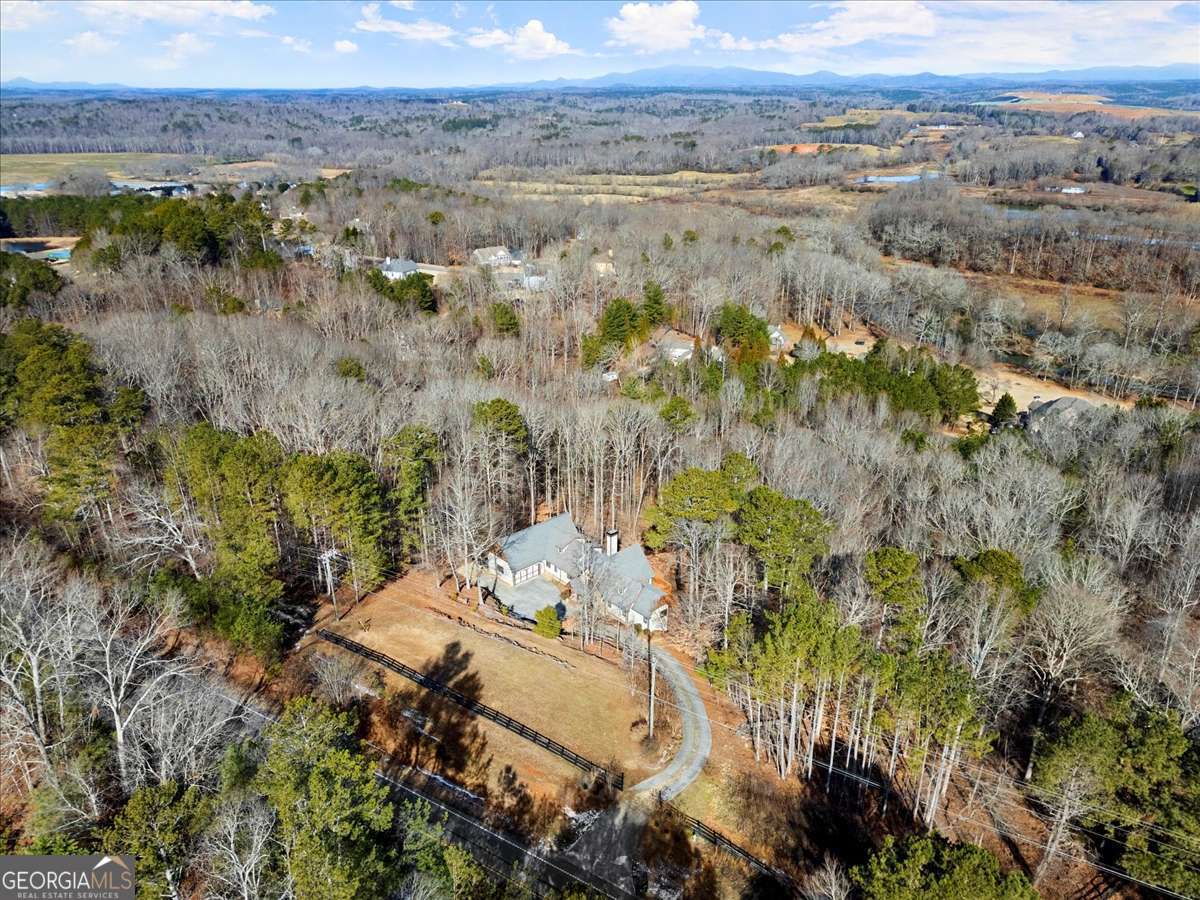 Welcome to this GORGEOUS TIMBER FRAME ESTATE! Nestled on over 2 PRIVATE, WOODED ACRES with an option to purchase an ADDITIONAL 2+ acre parcel to build a second home, barn, garage or just for your privacy and peace-of-mind. Enjoy direct trail access to the ETOWAH RIVER and beautiful LONG- RANGE VIEWS of the NORTH GEORGIA MOUNTAINS. This EXQUISITE, CUSTOM home provides a peaceful, country mountain setting while being conveniently located minutes from groceries, restaurants, an easy commute, and more!! Custom Designed by MILL CREEK POST & BEAM Co. This cedar and stone home features SOARING VAULTED CEILINGS, WIDE-PLANK PINE FLOORS, and MASSIVE EXPOSED BEAMS. The expansive great room features a TWO-SIDED STONE FIREPLACE and GORGEOUS WALL-TO-WALL WINDOWS which showcase views of the river valley and North Georgia Mountains beyond. Fine finishes include TONGUE AND GROOVE CEILINGS, SOLID ALDER DOORS, CUSTOM IRONWORK and so much more. Designed for energy efficiency and built to last centuries, the home is enclosed in STRUCTURAL INSULATED PANELS, which provide high R-Values and LOW energy bills. The cost to build this home today is well over 2M. The heart of the home is the GOURMET KITCHEN, with an 8-foot island and tons of cabinet space. Designed with the family chef in mind, high-end MONOGRAM appliances, GRANITE countertops, a SIX-BURNER cooktop, WARMING DRAWER, ADVANTIUM SPEED COOK OVEN, and GORGEOUS WALK-IN PANTRY will make cooking a joy. The country kitchen's dining space is centered around the FIREPLACE, and offers the PERFECT SPACE FOR ENTERTAINING with a fire and a view! Designed for ranch living, the MAIN-LEVEL PRIMARY SUITE features a PRIVATE COVERED DECK with indoor/outdoor living sliding doors, a SPA-INSPIRED BATHROOM, and a CUSTOM WALK-IN CLOSET. Two additional main-floor bedrooms share a JACK-AND-JILL bath. A half bath and a LARGE LAUNDRY ROOM with BUILT-INS are also on the main floor. A LOFT overlooking the GREAT ROOM would be a wonderful home office or private reading space. Upstairs is a second Master Suite with a LUXURY BATH and WALK-IN CLOSET. An EXPANSIVE BONUS ROOM offers FLEXIBILITY as a FIFTH BEDROOM or BONUS ENTERTAINMENT SPACE. The nearly 3,000 SQ FT UNFINISHED BASEMENT is already INSULATED and FRAMED with a FIREPLACE INSERT, offering ENDLESS POTENTIAL for CUSTOMIZATION. An awesome MAN-CAVE space with double-door access will give you a great place for home projects. Outdoors, enjoy 900 SQUARE FEET OF DECKING, a FENCED PADDOCK for dogs or ponies, and SERENE NATURAL SURROUNDINGS. Additional features include an OVERSIZED 750+ SQ FT GARAGE, COPPER GUTTERS, TANKLESS WATER HEATER, and PELLA ARCHITECTURAL, DOUBLE-PANE CASEMENT windows with wide overhangs to enjoy a nice breeze even when it rains! Zoned for TOP-RATED FORSYTH COUNTY SCHOOLS, and eligible for the FORSYTH COUNTY SENIOR TAX EXEMPTION, this home perfectly combines PRIVACY, the TRANQUILITY OF NATURE and LUXURIOUS LIVING close to MODERN CONVENIENCES. This is your OPPORTUNITY to OWN a TRUE NORTH GEORGIA MASTERPIECE that is PRICED WELL BELOW APPRAISED VALUE! This caliber of home doesn't come on the market very often! SCHEDULE YOUR PRIVATE SHOWING TODAY!!!