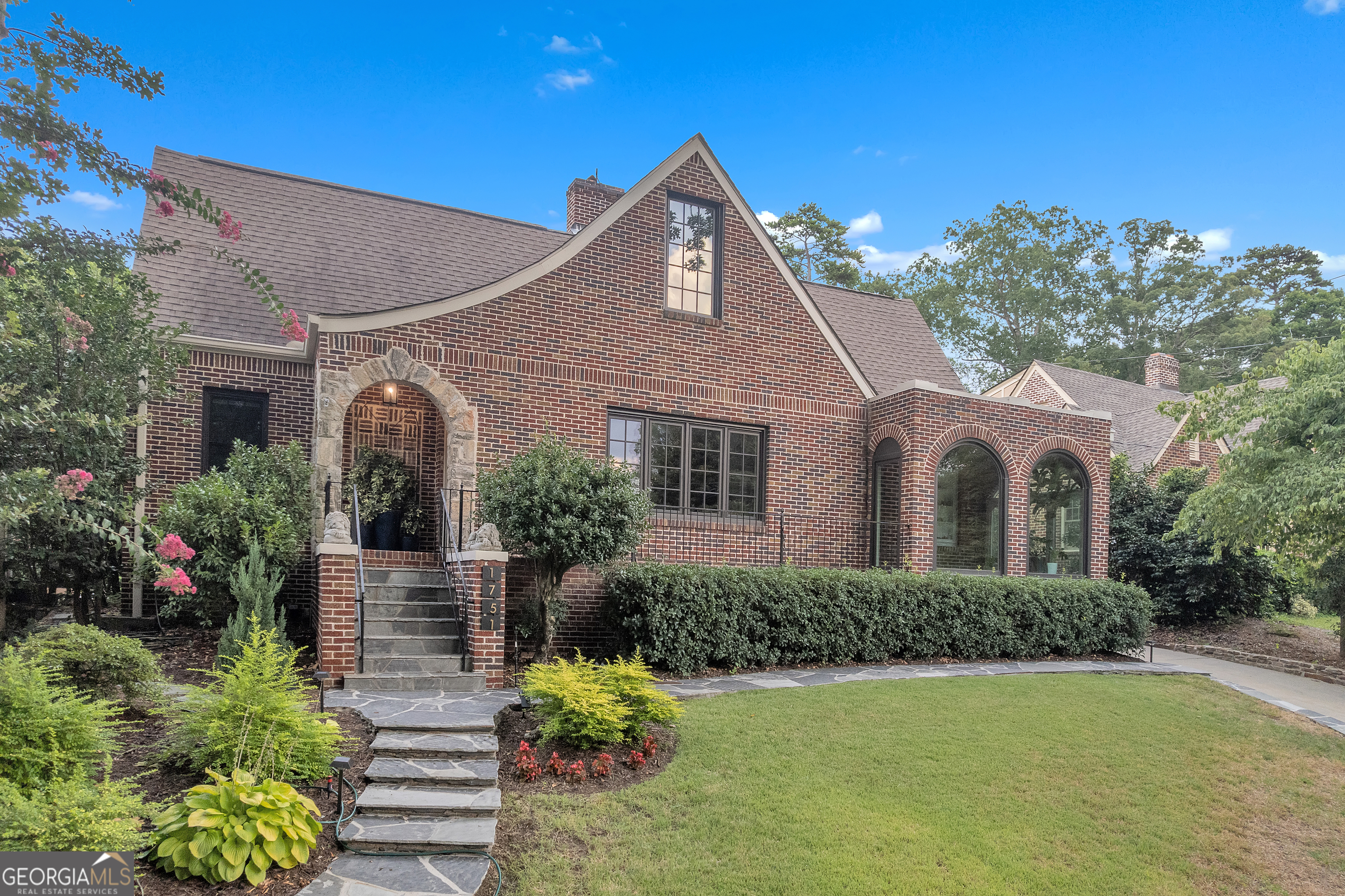 Classic Tudor architecture meets modern refinement in this exceptional Morningside residence, perfectly positioned on one of the neighborhood's most coveted streets. A stone path leads to an elegant stone archway and covered veranda, setting a stately tone before stepping inside. The interior impresses immediately with a grand living room with intricate fireplace detailing nods to the home's historic charm. The dining room connects effortlessly to a light filled sunroom and designer kitchen that will satisfy the most discerning chef-featuring a massive island with waterfall edge, quartzite countertops and professional grade appliances. The living space is extended to a sprawling rear deck-ideal for hosting with style-and a large open family room that anchors the home's main level. Two spacious bedrooms and two full baths round out this floor with both luxury and practicality. Upstairs the primary suite is a private escape with a custom walk-in closet, a deep soaking tub and luxurious shower. An additional bedroom, full bath, and a beautifully appointed office with french doors offer flexibility and function with elegant finishes throughout. This is refined intown living-rich in detail, uncompromising in quality.