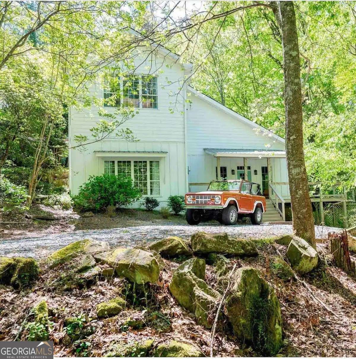This truly one-of-a-kind property offers an irreplaceable setting as it is nestled just feet from a year-round cascading waterfall and a creek that runs the full length of the expansive back deck. Homes with a natural feature like this are nearly impossible to find in today's market, and the serene beauty of this setting can not be replicated through new construction. Inside, the home features 3 bedrooms, 3.5 baths, plus a versatile fourth room ideal for use as a guest bedroom or office. The open floorplan is perfect for entertaining, enhanced by a wet bar, spacious living and dining areas, and seamless access to the large back deck-ideal for gatherings or peaceful outdoor living. The oversized master suite impresses with high ceilings and ample space, while the sunroom offers the perfect retreat to relax with breathtaking views of the creek and waterfall. Additional highlights include a 3-car garage and a separate outbuilding that could be utilized as a workshop or for extra storage. Conveniently located with quick access to GA 400, this home combines natural beauty, functionality, and convenience - making it a rare opportunity for both everyday living and entertaining. The home is currently being used as a rental. Please do not approach the home or access the driveway area unless a showing has been scheduled (as a courtesy to the current renters).
