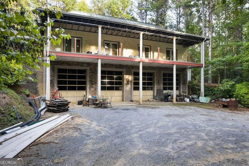 Rare, multi-use live/work opportunity on approx. 14 acres in Rockmart consisting of two tax parcels being sold together (Tax ID 057-118M is 10.16 Acres and 057-118T is the structure and 3.58 Acres). Built with industrial steel (per seller, rated for Category 5 hurricane conditions), this fortress-like structure delivers durability, security, and flexibility for a wide range of business and residential needs. Over 10,000 total square feet under roof, including approx. 2,000 sq. ft. of finished living space plus significant unfinished areas ready for build-out. Main level features 10' ceilings, hardwood floors, open-concept kitchen and living room, primary bedroom with full bath, laundry, an additional full guest bath, a massive covered porch, and approx. 2,000 sq. ft. of adjacent unfinished space for expansion. The upper level offers a guest suite with full bath, living/sitting area, and another approx. 2,000 sq. ft. unfinished area-ideal for additional bedrooms, offices, studio, or storage (finish as desired). The basement offers an astounding standout 4-stall automotive shop with mezzanine and its own full bath to supports trades, fabrication, vehicle storage, or gear-intensive hobbies. An outdoor covered area can function as a prep/serving kitchen, sheltered work zone, or covered parking. A rooftop outdoor area is designed for gardening, entertaining, or private relaxation. This property invites small business owners, homesteaders and/or entrepreneurs seeking space to both live and operate: think workshop, studio, catering/culinary production, e-commerce fulfillment, homeschool/co-op classroom, creative lab, or equipment storage. All subject to county approvals and zoning. Substantial unfinished square footage gives you the freedom to tailor interiors to your workflow, equipment, inventory, or future growth.Additional notes: bottom level is built into the hillside for a low-profile, insulated feel; multiple full baths (three in the finished living areas plus one in the shop) support daily living and on-site operations. Bring your business, bring your plans, and bring your elbow grease-this rare, industrial-strength property is ready to become your live/work headquarters. All figures are approximate; buyer to verify square footage, acreage, and intended use with the appropriate authorities.