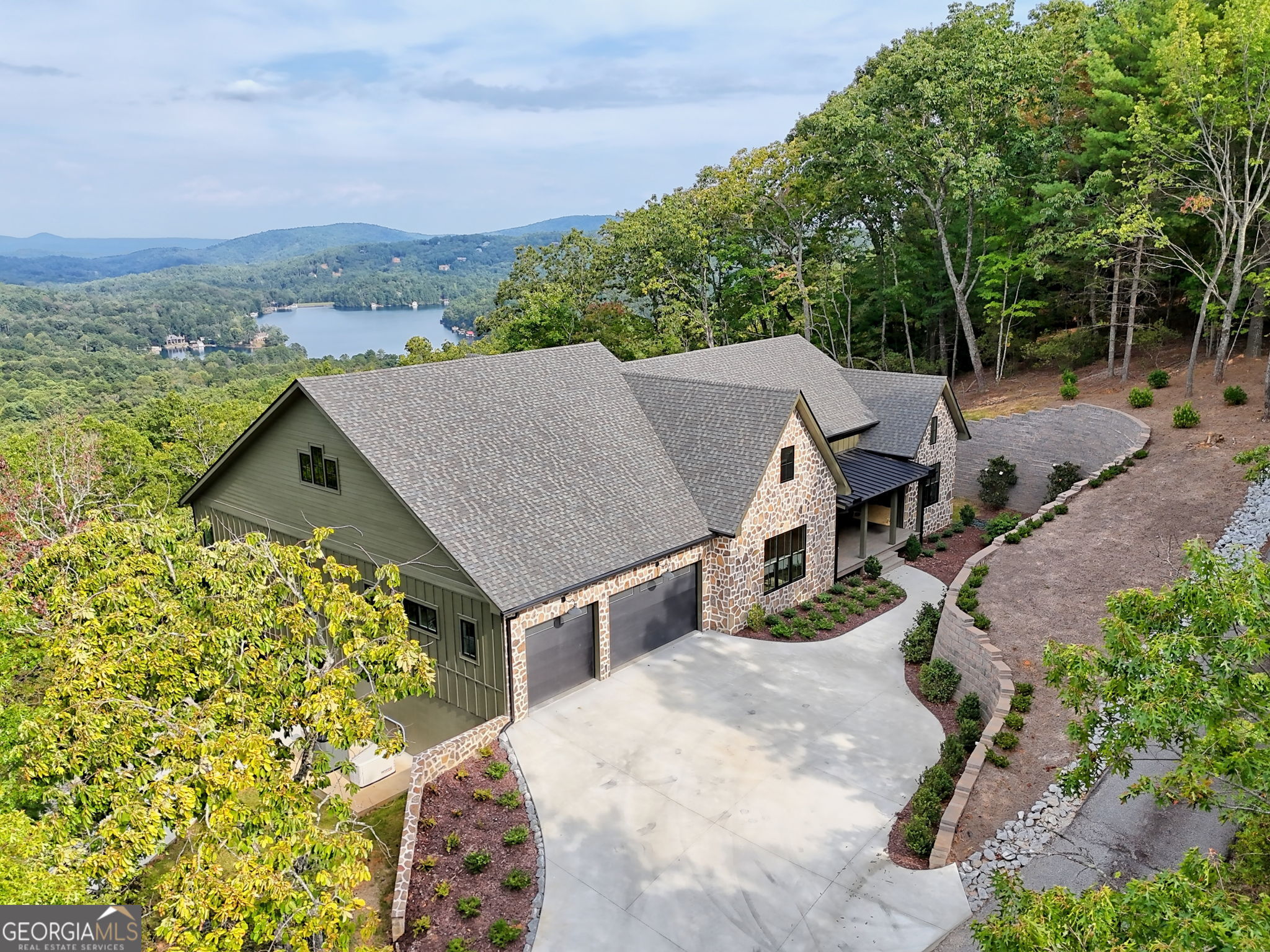 Introducing a newly constructed home that offers breathtaking layered blue mountain and lake views. Perched high on a ridge above the crystal clear waters of Lake Rabun, this mountaintop home offers 6,400 square feet of luxury living. Every room in this home is designed to bring the outside in, with floor-to-ceiling Pella windows offering views. The natural oak floors and light decor create a warm and inviting atmosphere. The open foyer and great room offer views all the way through the house to the central porch area. The porch, with retractable screens, ensures your comfort. The expansive kitchen features state-of-the-art appliances, quartzite countertops, and custom-built oak cabinetry. A wall of windows allows for plenty of natural light and extraordinary views. Doing the dishes will be a pleasure! The primary suite serves as a serene retreat, complete with a luxurious bath featuring heated floors, a soaking tub, and an oversized shower. Two walk-in closets with built-ins keep your personal items beautifully organized. Additional guest rooms and a spacious bath area provide a separate space that guests will appreciate. The main level includes an oversized garage built to accommodate a large SUV or truck, along with space for a second vehicle and an EV Charging station. A sunlit laundry room makes folding the laundry a pleasure, and the walk-in pantry is equipped with an additional refrigerator and freezer. Oak-built-ins line the hallway, maximizing storage space. On the terrace level, you will find an additional family room, perfect for movie nights, as well as a flex room that includes a Murphy bed and its own luxurious bath. An end guest room and bath offer private and comfortable space for additional family or guests.. The lower-level workshop, which has its own separate driveway and garage, provides an ideal hobby area for the entire family. This custom-built home was designed for full-time living and features thoughtful design that enhance comfort, safety, and sustainability. Notable elements include a whole-house generator, a water storage system for operation during power outages, and a water filtration system. Created by experienced homeowners with extensive knowledge from previous projects, this home is truly a forever home. Save yourself the time and uncertainty of building a custom home- This beautiful property is waiting for you!