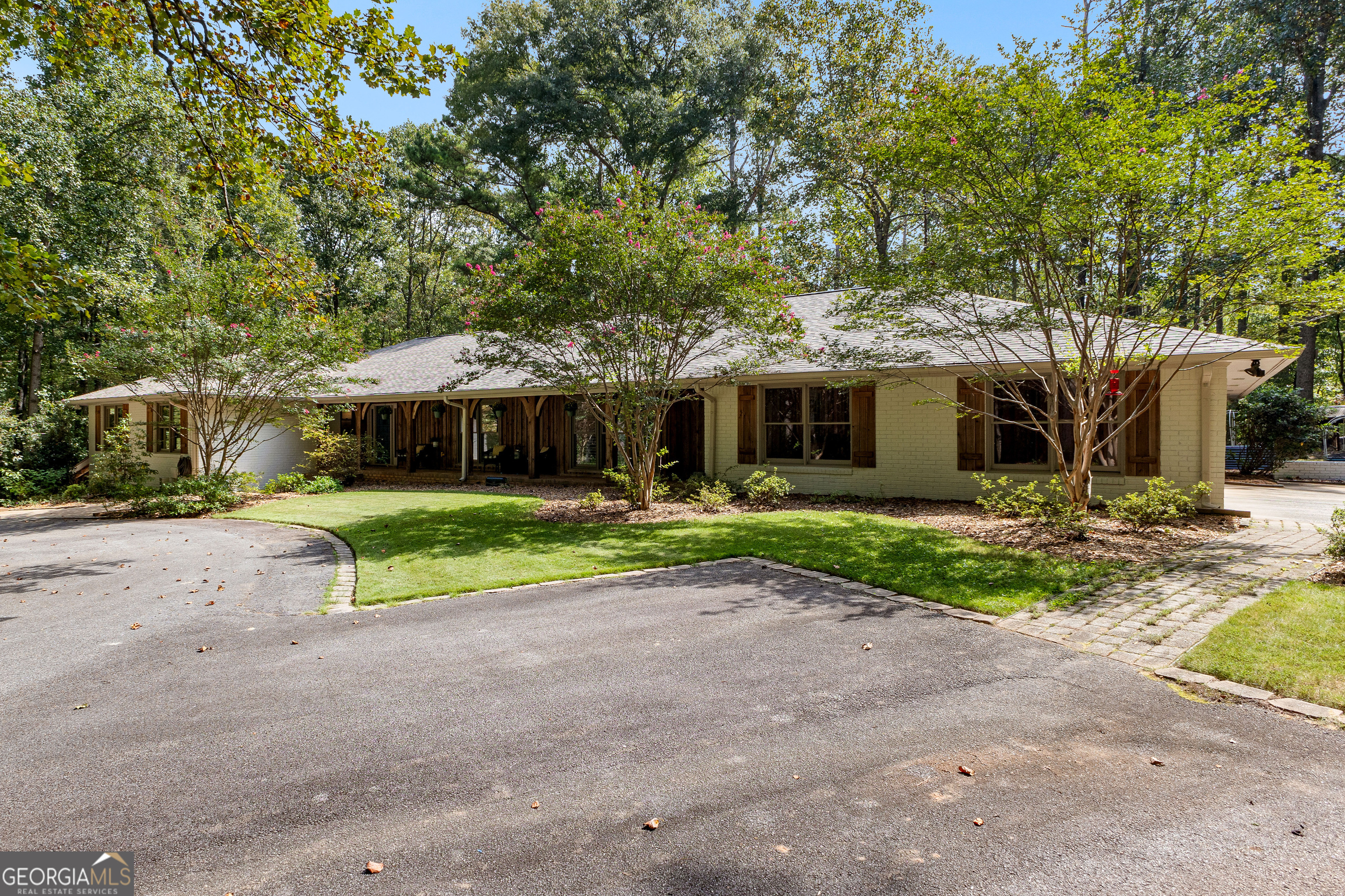 MUST SEE! One-of-a-kind private retreat on 8 wooded acres in a gated 110-acre community within the sought-after Whitewater school district! This quality-remodeled ranch offers over 3,000 sq. ft. on the main level plus a fully finished 2,000+ sq. ft. terrace level, perfect for multi-generational living or entertaining. Step inside to a light-filled, open floor plan featuring skylights, a stunning centerpiece fireplace, hardwood floors. The updated kitchen boasts soft-close cabinetry, granite countertops, a custom wood hood vent, and a spacious island that opens seamlessly to the dining and family rooms. Enjoy your morning coffee year-round in the heated and cooled tiled sunroom overlooking the natural landscape. A updated half bath and office with French doors complete this space. The luxurious main level primary suite is your personal retreat, with a huge walk-in closet and spa-like bath showcasing a glass walk-in shower, soaking tub, dual granite vanities, and marble travertine tile. Step out to your own private balcony and take in the serene wooded views. Two additional spacious bedrooms with double closets and a large full bath complete the main floor. The freshly painted terrace level is designed for flexibility, offering a full second kitchen, family room with fireplace, two bedrooms, a full bath, game/rec room, and abundant storage. With a separate drive, entrance, and covered patio, it's ideal for guests or extended family. Outdoors, you'll find thoughtful extras including a brick smoker, a 24' x 35' outbuilding with two large roll-up doors, chicken coop and an additional workshop/storage room attached to the 3-car carport. No worries when the power goes out-the backup propane-powered generator kicks in automatically so you won't miss a beat! Your daily drive through the gated community winds past creeks teeming with wildlife, creating a serene, mountain-like setting while enjoying peace, quiet, and access to a common park and picnic area. This rare property combines modern updates, quality construction, and unmatched privacy - all in a convenient Fayette County location. Don't miss your chance to make it yours!
