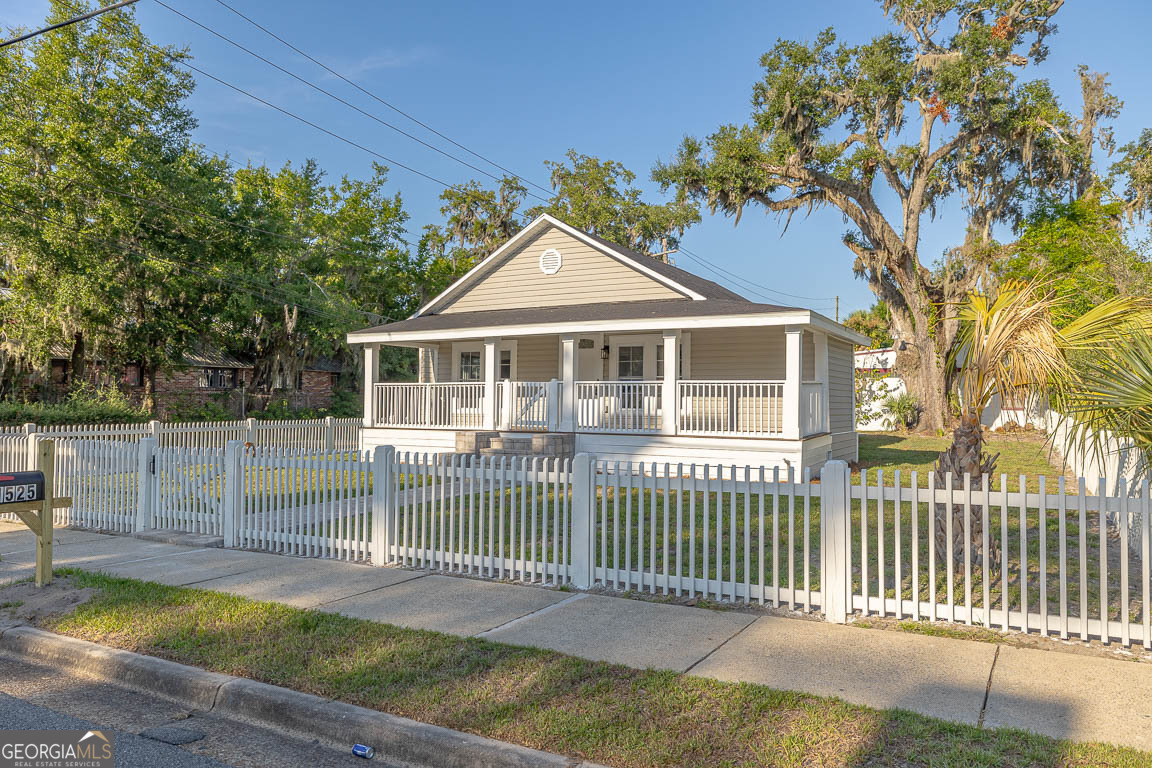 Welcome to 1525 Tillman Avenue, where timeless charm meets modern comfort! This beautifully renovated 3-bedroom, 1.5-bath home features a spacious wraparound front porch, perfect for morning coffee or evening relaxation. Nestled behind a classic white picket fence, the home offers eye-catching curb appeal with a brick paver walkway leading to the front steps. Step inside to find: LVP flooring throughout, exposed wood ceiling beams adding warmth and character, Open-concept layout connecting the living, dining, and kitchen areas. Updated kitchen with wood cabinetry and butcher block countertops. Neutral color palette and new windows for natural light, All-new electrical wiring and updated plumbing with new A/C system (2024) and spacious laundry room. Plenty of parking space at the back! Located 10-15 minutes form Saint Simon Island and just minutes from downtown Brunswick, shopping, dining, and local attractions, this move-in ready home blends historic charm with modern living - inside and out.