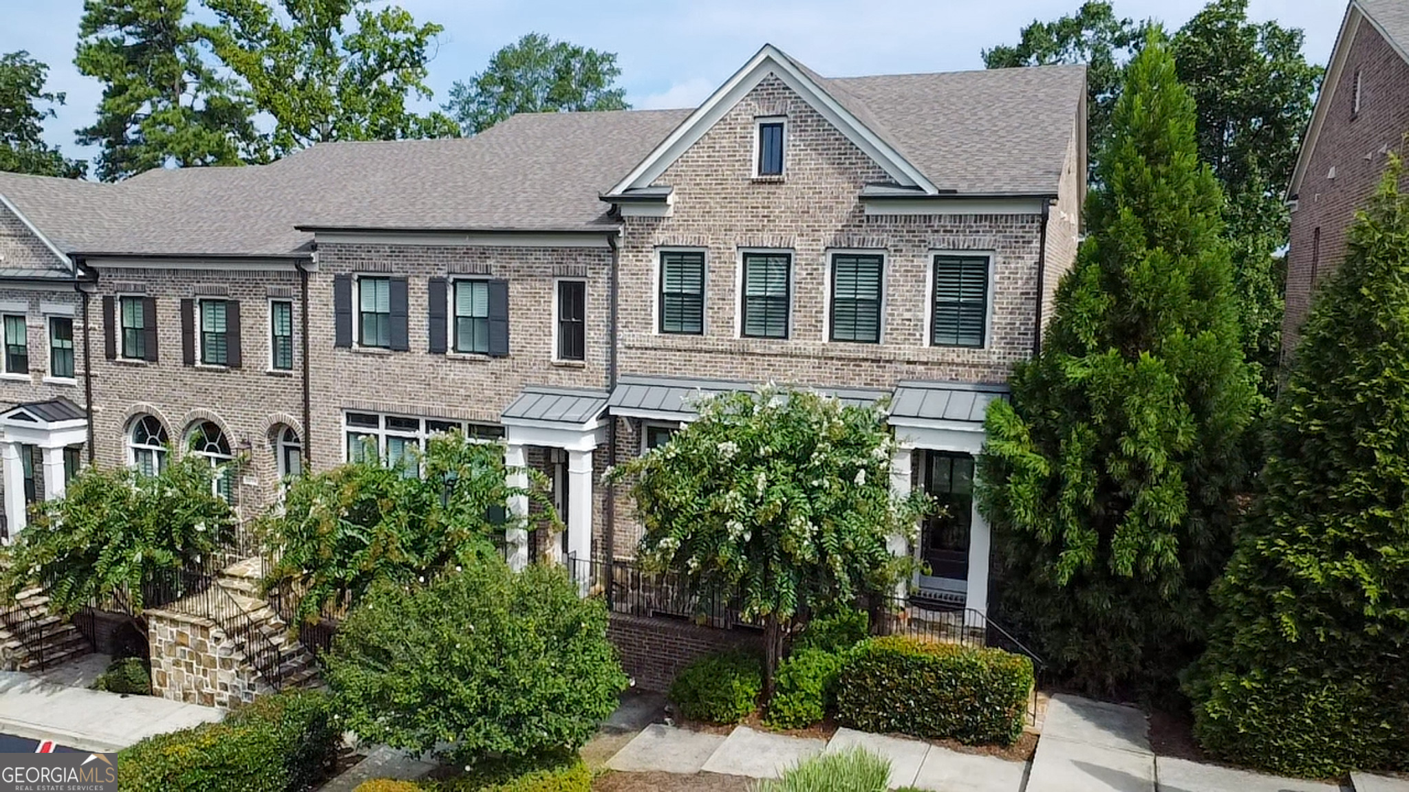 All brick townhome with ELEVATOR, located in the sought-after Arrington Place community in Brookhaven. Designed for today's lifestyle, this boutique enclave offers refined living with an open floor plan and a separate formal dining room perfect for entertaining. The gourmet kitchen is a chef's dream, featuring an oversized island with casual dining, KitchenAid appliances, a custom vent hood over the gas cooktop, glass-front cabinetry with lighting, under-cabinet wine fridge, and pull-out shelving. Rich hardwood floors flow throughout the main level. The spacious living room boasts a cozy fireplace and built-in bookcases, while French doors open to a large deck with stunning Buckhead skyline views. An irrigation system ensures easy maintenance for outdoor spaces. Upstairs, the inviting primary suite includes a private sitting area, deluxe bath with soaking tub, glass-enclosed walk-in shower, double vanity, and an oversized walk-in closet. A second bedroom with en-suite tile bath completes the upper level. The versatile terrace level offers a third bedroom and full bath, along with access to the two-car garage. An elevator services all floors, providing comfort and convenience. Positioned in a prime location within the community, this home overlooks green space and beautifully maintained landscaping. Just minutes from Buckhead, with easy access to Midtown and Emory, this residence combines elegance, functionality, and unmatched convenience.