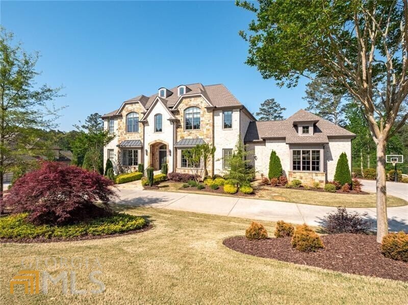 Sophisticated style and award-winning builder in Milton's popular Manor Golf and Country Club. Absolutely stunning home overlooking the 17th fairway and features soaring 12-foot ceilings, an open floorplan, owner's suite on main, covered patio with fireplace, two kitchens, finished terrace level, wine cellar, and infinity edge saline pool and two laundry centers. The main floor features a large kitchen with oversized island, marble countertops, a professional 48" gas range, and built-in refrigerator/freezer; drop zone/mud room with custom cabinet doors and sitting bench; a secondary kitchen with oven/cooktop, refrigerator, and walk-in pantry; wine cellar and bar with beverage cooler. The second floor includes four en-suite secondary bedrooms; a large open foyer and media room with built-in entertainment center, and upstairs laundry center. Terrace level features two en-suite guest bedrooms, gym, large great room with cabinetry and beverage center, golf simulator and access to the outdoor pool and patio. The outdoor area is breathtaking with limestone style pool decking, sheer decent saline pool, outdoor grill kitchen with bar seating and covered patio. Styled to perfection this home shows like a model and will certainly please the most particular buyers.