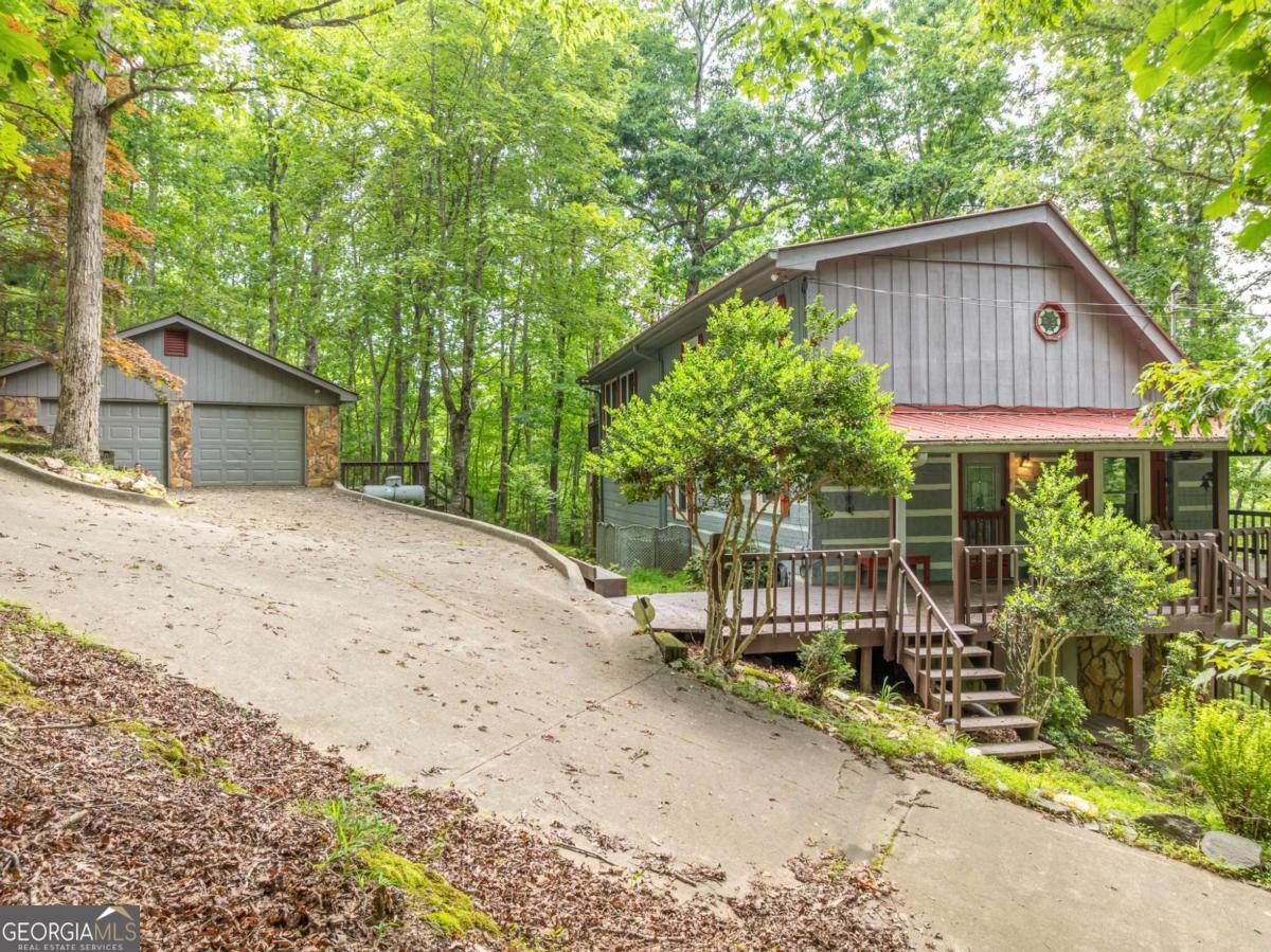Long Range Seasonal Mountain View Chink Log Home 4-bedroom, 4-bathroom cabin with a Two Car detached garage. This home is perfectly designed for short-term rental, a second home, or full-time mountain living. Private setting with frequent visits from local deer, this property offers both tranquility and adventure for those who love the outdoors. Inside, you'll find a spacious open concept gathering area with a cozy fireplace surrounded by stone, dining space, and a well-equipped kitchen featuring granite countertops and rustic wood accents. The main level boasts two bedrooms, including a huge primary suite with conveniently located laundry nearby. Upstairs, a large private loft suite features a full bedroom and bath, while the lower level offers another full bedroom, bunk area, and additional entertainment space. Step outside and take in the long-range mountain views from the covered porches, unwind in the hot tub, or challenge friends to a game on the pool table. With a beautiful blend of real log and wood siding, along with high-end finishes like rock, wood, tile, and granite, this home is a true mountain retreat. Whether you're sipping morning coffee on the porch or enjoying a glass of wine under the stars, this property offers the perfect escape. Coosawattee River Resort offers seasonal weekly concerts, pickleball, tennis, swimming, fishing, and activities for all ages.
