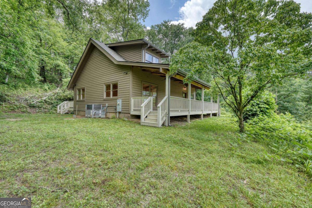 Nestled just north of downtown Clayton in scenic Rabun Gap, this beautifully renovated 3-bedroom, 2-bathroom home offers the perfect blend of modern updates and mountain charm. Set on a private one-acre lot, the home features a brand-new roof, siding, HVAC, flooring, kitchen cabinets, counters, and both front and back porches. Inside, the great room showcases striking exposed beams and an original brick fireplace that adds timeless character. The main level includes two bedrooms and one full bath, while the upper level offers a private bedroom and bath. Enjoy outdoor living on the wide covered front porch or the spacious open back deck. Additional features include a paved driveway, carport, and convenient laundry area off the kitchen's dining space. Whether you're looking for a full-time residence or a peaceful mountain getaway, this home is move-in ready with the warmth and charm you won't find in a new build.