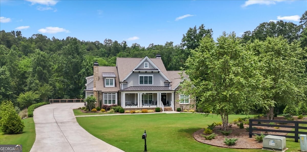 Experience the rare opportunity to own a truly extraordinary estate nestled on 2 private, park-like acres with stunning frontage on the serene Sharp Mountain Creek. This one-of-a-kind luxury residence offers the perfect blend of natural beauty and refined living - where the soothing sound of flowing water, lush landscaping, and complete backyard privacy create an unforgettable setting. Tucked away in an exclusive cul-de-sac, this meticulously craftsman style home features 5 spacious bedrooms, 5 full bathrooms, and 2 half baths, with luxurious finishes and thoughtful details throughout. The backyard is a masterpiece in itself - a tranquil retreat complete with a firepit, hot tub, expansive deck, and screened porch all overlooking the creek and beautifully manicured grounds. Step inside to discover timeless elegance and elevated design. Rich hardwood floors throughout, an open floorplan, wide plantation shutters, and detailed millwork set the tone, while walls of windows invite in the light and frame peaceful views of the landscape beyond. At the heart of the home, a chef's kitchen impresses with custom white cabinetry, upgraded GE Monogram appliances, quartz countertops, a large island, farmhouse sink, wall-mounted pot filler faucet, and a stunning wood-trimmed range hood. The kitchen flows effortlessly into a vaulted keeping room with a stone fireplace and rustic wood mantle - perfect for gathering. A grand family room with coffered ceiling, built-in bookshelves, and a second stone fireplace offers additional space for relaxed luxury living. A formal dining room easily accommodates large-scale entertaining. The main-level primary suite is a private sanctuary featuring a sitting room, trey ceiling, hardwood floors, large walk-in closet, and a spa-like ensuite with quartz countertops, dual vanities, a soaking tub, and an elegant custom tiled shower. The main level also features two powder rooms, a drop zone, and a well-appointed laundry room with a quartz countertop sink. A private staircase leads to an expansive bonus room offering endless possibilities for a playroom, guest suite, or home office. Upstairs offers three thoughtfully designed bedrooms, each with its own ensuite bath, ensuring ample space and privacy throughout. The terrace level provides a seamless extension of the home's living space - complete with a second kitchen, inviting media room, private guest quarters, bathroom with double vanities, fitness room, and a beautifully appointed family room perfect for entertaining in style. Every element of this home reflects thoughtful planning and elevated living- including extensive storage solutions throughout, complemented by a custom-built storage room discreetly tucked beneath the deck. Premium upgrades abound, from the spacious 3-car garage and expansive driveway to the state-of-the-art tankless water heater, whole-house generator with surge protection, irrigation system, and high-efficiency gas furnace equipped with advanced overflow prevention for seamless comfort year-round. Located in a top-rated school district, this exceptional property also offers convenient access to the interstate and is just minutes from the charming and vibrant downtown Ball Ground - home to locally loved restaurants, boutiques, and seasonal events. This is more than a home - it's a tranquil creekside sanctuary where elegance, serenity, and luxury come together in perfect harmony.