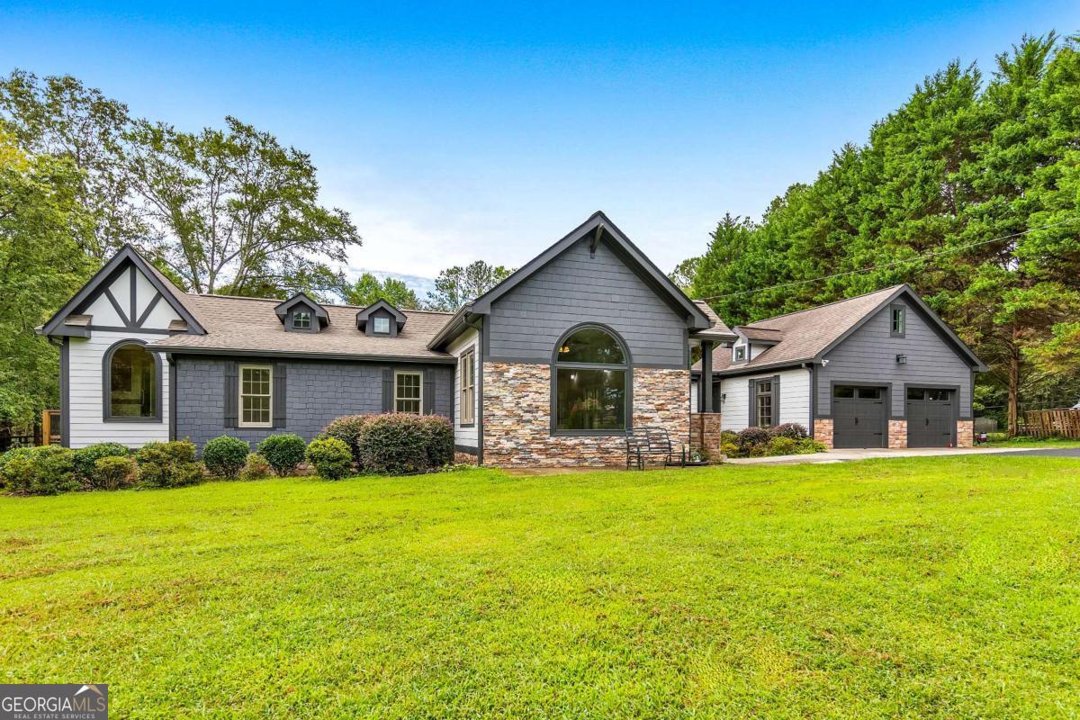 Discover the perfect private retreat in the heart of Woodstock! Nestled on 1.55 acres behind a private gated entrance, this inviting 3 bed / 2.5 bath craftsman ranch home combines timeless design with thoughtful updates. Inside, a sun-filled layout welcomes you with a formal sitting room, dry bar, and dining area. The home features LVP flooring and soaring 10-12 ft ceilings throughout. The elegant kitchen is complete with granite countertops and stainless steel appliances, including an LG electric range and refrigerator. The fireside living room offers a cozy retreat, while the primary suite impresses with its own electric fireplace and spa-like bath featuring a granite double vanity, jetted tub, and separate shower. Two additional bedrooms share a full hall bath, and a convenient hallway laundry closet comes complete with a washer and dryer. Recent upgrades include a roof within the last 5 years, a new deck with cedar-top railings & pine bottom wood, gutter guards, vapor barrier & fans in the crawlspace, and a detached two-car garage connected by a breezeway. With low utility bills, this home offers both comfort and efficiency. Outdoors, enjoy a fenced yard, well water for gardening, and a variety of fruit trees including cherry, pear, apple, peach, plum, and fig, along with Scuppernong grapevines and muscadine. Four storage sheds and a chicken coop complete the property, delivering a true homestead feel with modern conveniences.