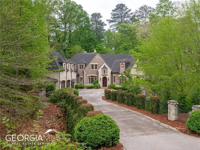 This ultimate, gated oasis sits on a private 1.5+/- estate amidst breathtaking, perfectly manicured grounds. This home is an entertainers' paradise w/fully updated, oversized interior & exterior spaces to accommodate endless possibilities. The formal entrance foyer leads to a gorgeous dining rm, newly renovated kitchen w/marble counters & stainless appls, adjacent to a keeping rm w/fireplace. Light filled living room offers 3 sets of French doors that open onto the patio overlooking the beautiful backyard, ideal for gatherings of any size or scale. Fireside master-on-main w/massive closets, bath w/dual vanities, garden tub, shower, & heated floors. The handsome office connects to the master suite as well. The grand staircase leads to 4 bedrooms w/en-suite baths & 2nd laundry on the upper level. The 4th bedroom over the 3 car garage also includes a kitchenette, ideal for au-pair. Stunning terrace level includes gym, living rm, movie rm, wine cellar, steam rm, full bar & in-law suite. Truly jaw-dropping, one-of a-kind backyard was thoughtfully designed by landscape architect Gerald Evje of Southern Impressions. These gorgeous grounds are complete w/connecting walking trails, boulders, waterfall, oversized heated saltwater pool, spa, putting green, fire pit & zipline. Hundreds of landscape lights, bistro lights & several oversized moon lights as well as the evening pool & jacuzzi lights make the entire home glow across all fronts. Guests can reside in the fully equipped custom two-story cabin in the backyard. The cabin has a large front porch, living rm, kitchenette, full bath & bedroom. State of the art technology abounds in the interior & exterior of the home & cabin. Full security camera system across the exterior property.