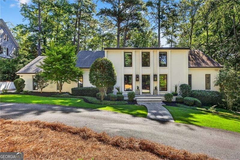 Stunning renovation by Amanda Orr in the heart of Vinings, blends timeless architecture with modern luxury. Refined finishes and a thoughtful floor plan make this home both an entertainer's dream and a private retreat. Inside, soaring ceilings, abundant natural light, and custom millwork set the tone. The chef's kitchen features top appliances, a large island, and open flow to the fireside living room with a wall of windows overlooking the lush one-acre lot. A mudroom and two-car garage w/ EV charging station add everyday convenience. The main-level owner's suite offers a spa bath, oversized walk-in closet, and sitting area. Upstairs are three spacious secondary bedrooms. The finished terrace level provides a living area, bar, and guest suite-ideal for entertaining or relaxing. Minutes to Vinings Jubilee, The Battery, and top schools, this home perfectly combines suburban tranquility with easy city access.