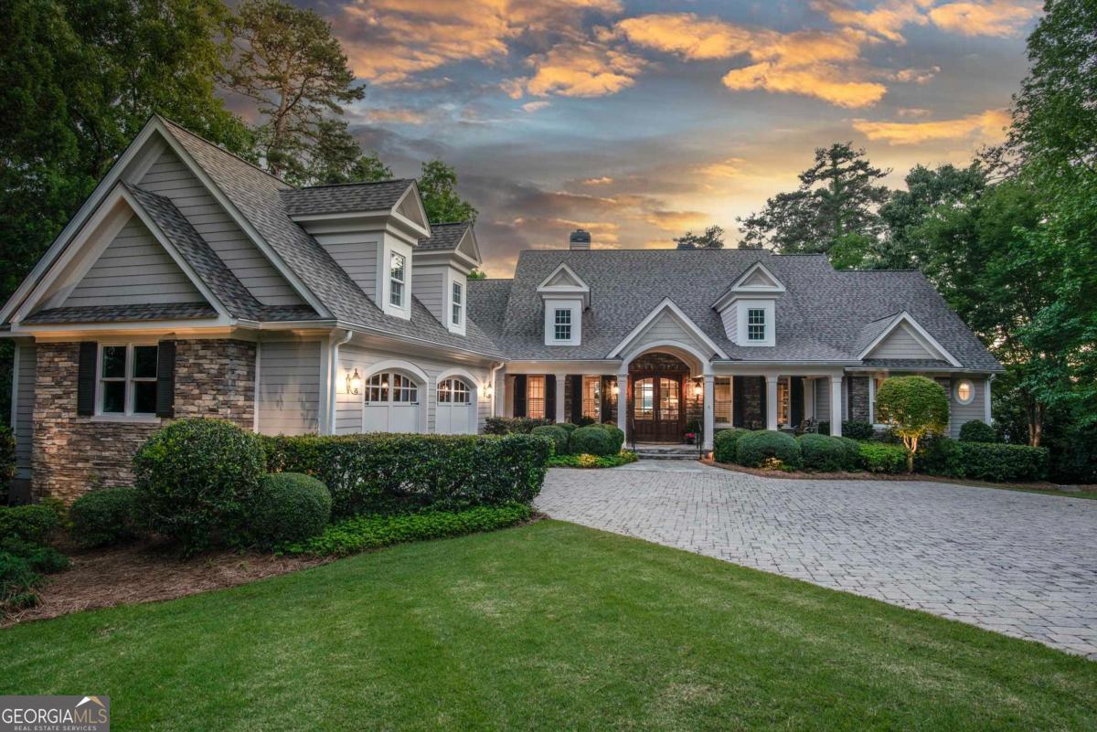 BEAUTIFUL CUSTOM HOME OFFERING UNOBSTRUCTED LAKE AND SUNSET VIEWS EVERY EVENING AT REYNOLDS LAKE OCONEE. As you enter this beautiful Reynolds Lake Oconee home, floor to ceiling windows frame an expansive, uninterrupted lake view across a prized sunset lot. Thoughtfully designed for effortless living and entertaining, the main floor features a spacious primary suite and an en suite guest bedroom, offering the convenience of one level living without compromise. Off the entrance foyer, a private office with custom built in bookshelves offers a refined workspace, while a formal dining room nearby is designed for entertaining and special celebrations. Beyond the foyer, the soaring great room and adjoining keeping room come together to create a light filled, expansive space for gathering, complimented by dual fireplaces and framed by panoramic lake views. The chef's kitchen showcases a large island, custom cherry wood cabinetry, and a matching range hood, seamlessly connecting to a charming sunroom with vaulted ceilings and an adjacent grill deck for easy outdoor dining. Rich finishes and detailed millwork lend timeless elegance and warmth throughout. The gracious primary suite enjoys direct walkout access to the deck overlooking lake, large windows capturing every sunset, and a luxurious bath with a soaking tub, walk-in shower, and expansive closet. A stylish powder room, laundry room, elevator, and convenient wet bar complete the main level. Descend to the lower level via elevator that offers a spacious family room, full bar, and game room ideal for hosting or relaxed evenings. Two additional guest suites with private baths provide generous accommodations, and multi level patios extend the living space outdoors, perfect for lakeside dining, entertaining, and enjoyment. Privately tucked away on a quiet culdesac in Falling Creek, this home offers a rare blend of privacy, community, and premier access to Reynolds Lake Oconee's top amenities. Enjoy being just steps from the walking trail and minutes from the new Richland Pointe golf course and restaurant. With its own private dock, you're only a short boat ride from the prestigious Jack Nicklaus designed Great Waters course and have a front row seat to Lake Country's best Fourth of July fireworks show. Membership available.