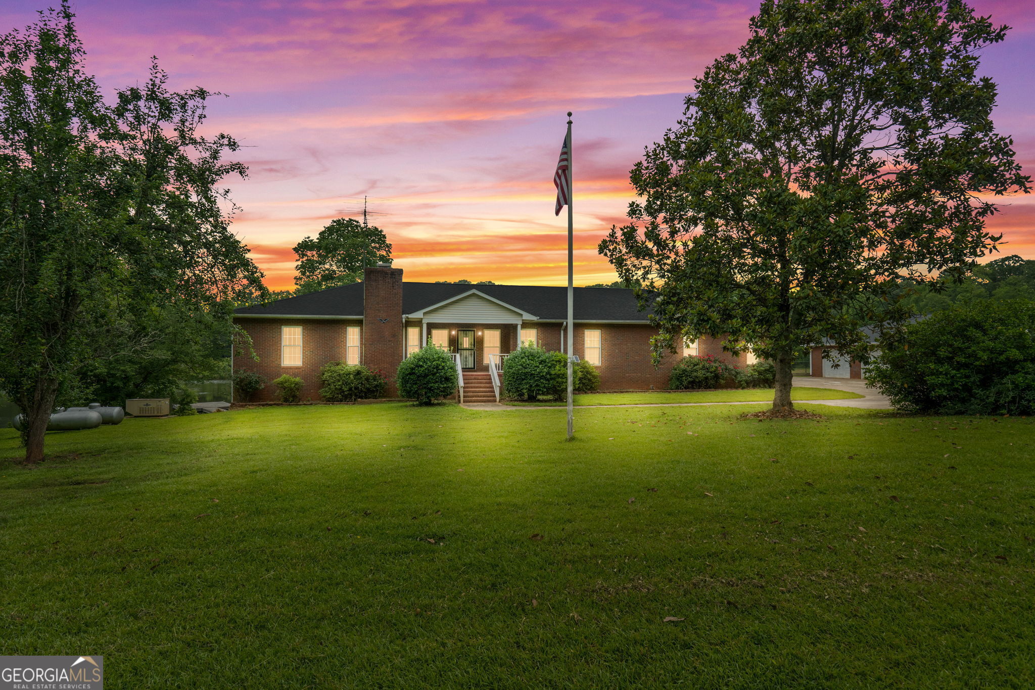 Welcome to 394 Hunter Road-an exceptional gated estate nestled on nearly 49 acres in the peaceful north end of Pike County. Though the mailing address is Griffin, this property is fully located in Pike County, offering the benefits Pike County serenity. As you arrive, a gated entry leads to a concrete driveway with ample parking and a private, peaceful setting. The four-sided brick home is situated just steps from a scenic pond and surrounded by landscaped grounds that include fruit trees, rose bushes, flowering shrubs, and open green space. The property includes multiple outbuildings: a three-car detached brick garage that matches the home, a 18x20 enclosed barn with a roll-up door, and a high-quality red-iron pole barn with a dirt floor-ideal for equipment, trailers, or agricultural use. The main house also offers an attached two-car garage. Inside, you're welcomed by a large living room featuring a floor-to-ceiling brick fireplace with granite accents, designed to be used with gas or wood. The oversized kitchen includes a center island with a six-burner cooktop, built-in microwave and oven, dishwasher, abundant cabinet space, and both a breakfast area and a formal dining area. Off the main living space is a bright sunroom with expansive windows overlooking the pond. The spacious owner's suite features a large walk-in closet and an en suite bathroom with a double vanity, makeup prep area, garden tub, separate shower, and water closet. Two additional guest bedrooms are generously sized with ample closet space and share a well-appointed hall bathroom. The home also features a massive laundry room with an additional storage closet. The unfinished basement offers a full footprint of the main level and is already stubbed for plumbing and equipped with electrical-providing incredible potential for expansion, storage, or workshop space. Additional features include a tankless water heater, whole-house generator, and a hidden safe room for secure storage. The property is serviced by a private well with a filtration system and a septic tank. Trails throughout the acreage allow for easy access by foot or ATV, making this a true multi-use property perfect for recreation, farming, or private retreat living. With its stunning setting, abundant space, and thoughtful design, this one-of-a-kind property is a rare find in Pike County. Schedule your showings today!