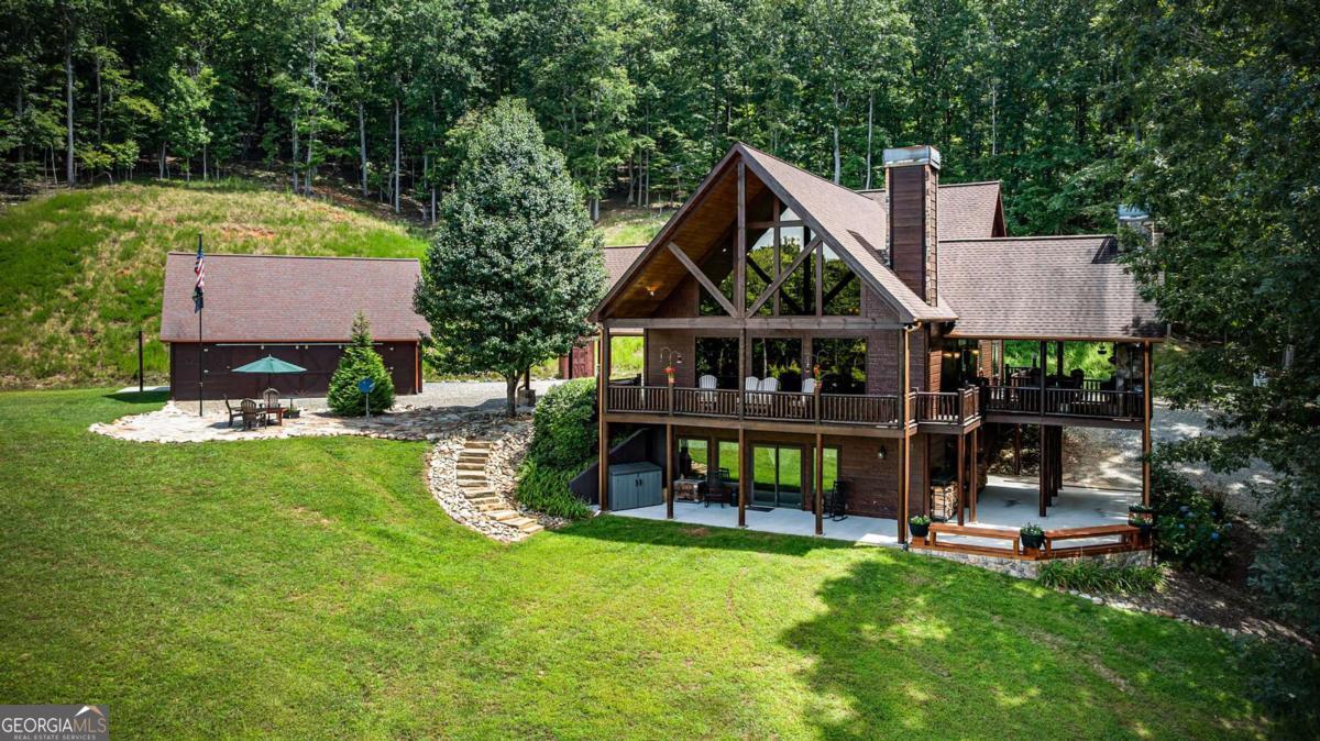 Gorgeous Mountain Lodge on 11.5 Acres!!! A True North Georgia Retreat Escape to your own private mountain paradise with this spectacular lodge, nestled on 11.5 pristine acres and bordered by U.S. Forest Service land for unmatched seclusion! Designed for both comfort and functionality, the property includes a versatile workshop/garage with storage space and a serene small stocked pond. Step inside the magnificent great room, where a dramatic wall of windows frames breathtaking vistas, while beautiful hardwood floors and a soaring stacked-stone fireplace with a Harman Pellet Stove insert set the tone for mountain lodge living at its finest. The open-concept design flows seamlessly into the large dining area and a chef's kitchen with recently upgrades appliances, featuring granite countertops, double ovens, prep sink, and a solid cedar 8-person bar perfect for gatherings. The main level offers two spacious bedrooms with walk-in closets, a stylish full bath with tiled shower, and a convenient laundry room. Upstairs, the expansive master suite impresses with a private deck, walk-in closet, luxurious spa bath with a 2-person tub, tiled shower, double vanities, and a private water closet. The terrace level is built for comfort and versatility, offering two additional bedrooms, full bath, wine and cigar room, wood-burning stove, safe room, and abundant storage. Outdoor living is equally impressive with wrap-around covered porches, a party deck with outdoor fireplace, and long range mountain views that set the stage for unforgettable entertaining or peaceful solitude. Modern comforts include dual HVAC systems (one dual fuel), tankless hot water heater, and energy-efficient Pella windows. This exceptional property is more than a home it's a lifestyle, where privacy, luxury, and natural beauty come together in the heart of the North Georgia mountains.