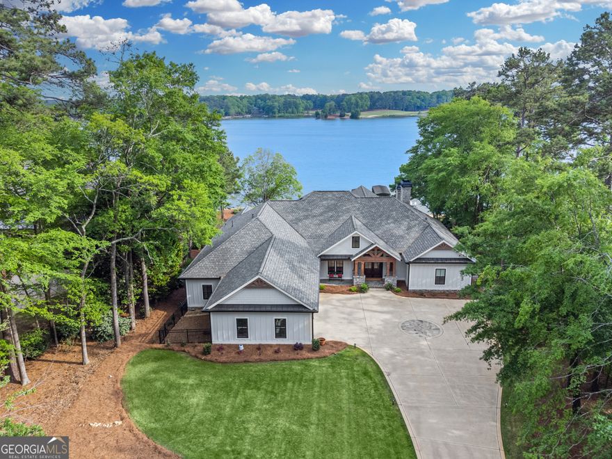 "NEW" COMPLETELY REMODELLED AND RENOVATED LUXURY LAKE HOME WITH PANORAMIC VIEWS in Reynolds Lake Oconee. Situated on a rare sprawling, flat lakeside property, this 9,000 sq ft home offers breathtaking spectacular views of the lake, sunset and golf course vistas, setting the stage for an unparalleled lifestyle. This expansive home has been meticulously gutted and renovated, effectively transforming it into a brand-new residence. The open floor plan greets you with stunning lake views, a grand great room,large porch with fireplace and seamless transitions to the dining area and a state-of-the-art Chef's kitchen. This brand new kitchen is equipped with top-tier appliances and countertops, custom cabinetry, making it a perfect blend of functionality and style. Built with the entertainer in mind, the home features a striking designer glass wine cellar that enhances the sophisticated ambiance of the living space. The main level boasts a vast master suite complete with a fireplace, sitting area, and awe-inspiring lake views. The opulent master bath is akin to a private spa, adorned with chic designer touches, a luxurious steam shower, and expansive walk-in closets.This level also houses three elegantly appointed guest suites, a bespoke custom office space, and a functional laundry room equipped with a dog shower and custom lockers. Rich, wide-plank hardwood floors throughout lead you to the lower level, accessible by an elevator. The terrace level unfolds into a vast entertainment hub with a large family and game room, a second indoor full kitchen,and  a second dining area convenient to the large outdoor kitchen. This level is enriched with another spacious bedroom suite and bath, powder room, a bunk room, a gym, and a flexible bonus room and second laundry room. There is an abundance of storage space for your lake toys. Wired for Smart home technology. Glass doors open to a sprawling outdoor living area, featuring a comprehensive kitchen, a substantial pool with an integrated spa, fire pit, outdoor shower and extensive large landscaped flat backyard  that merge seamlessly with the lakefront. Enjoy family barbecues, cornhole, volleyball and endless outdoor activities or simply relax by the water's edge before getting on your boat for a sunset cruise. Welcome to your ultimate lakefront paradise in Reynolds Lake Oconee.This estate offers a lifestyle that epitomizes lake luxury, making every day feel like a vacation.Membership is available.