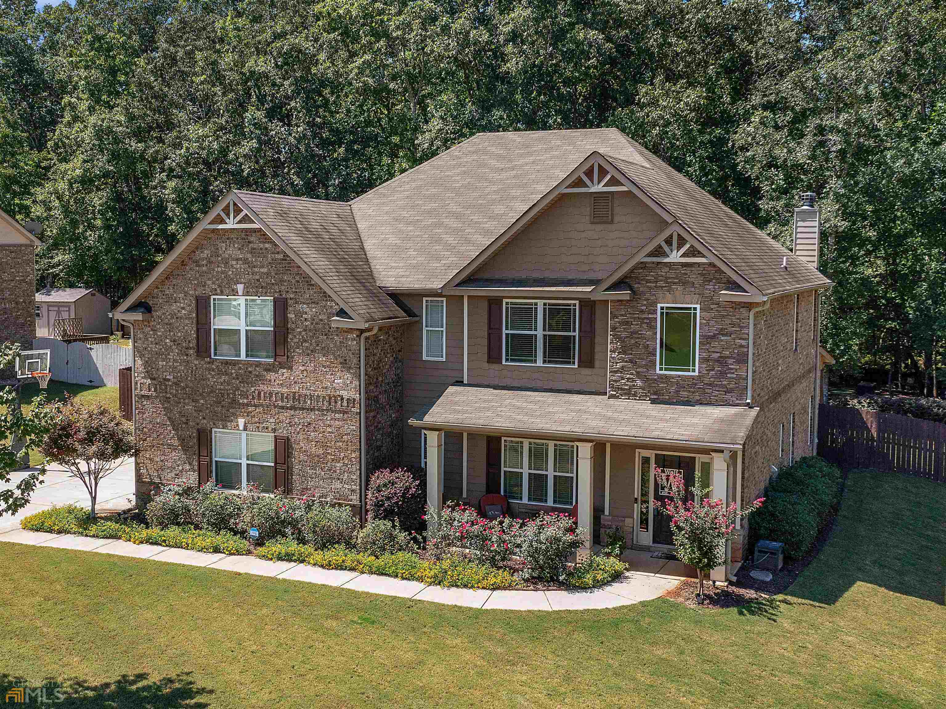 One of a kind spacious brick home right in the heart of Ola, near all the sought-after Ola schools and the new Publix shopping center. Room for everyone in this 5 Bedroom 4.5 Bath home! Largest floor plan in neighborhood with over 3400 square feet and unique upgrades throughout! Relaxing front porch welcomes you into a 2-story foyer with hardwood floors and open staircase. Architectural details and trim highlight the open floor plan, great for entertaining yet cozy for family living. Foyer opens to a formal dining room with coffered ceiling, beautiful eat-in kitchen with contrasting island features granite countertops, tile backsplash, 42" cabinets, stainless steel appliances, and hardwood flooring. Huge 2-story family room with catwalk and a spacious keeping room with fireplace at the rear of the main level. Also on the main level is a guest suite complete with a full bath just perfect for the in-laws! Upstairs you will find a supersized owner's suite with sitting room, luxurious bath with dual vanities, soaking tub, separate shower, and a large walk-in closet. Also upstairs are three more large secondary bedrooms each with nice size closets; one has a private bath. There's also a hall bath for the other bedrooms to share! Enjoy cookouts on your oversized covered patio overlooking a fenced park like backyard with athletic cage that can be used for baseball, softball, golf, etc. and an outbuilding for storage! You will love this inviting private retreat for entertaining or just hanging out with the family! See it today or you will miss out!
