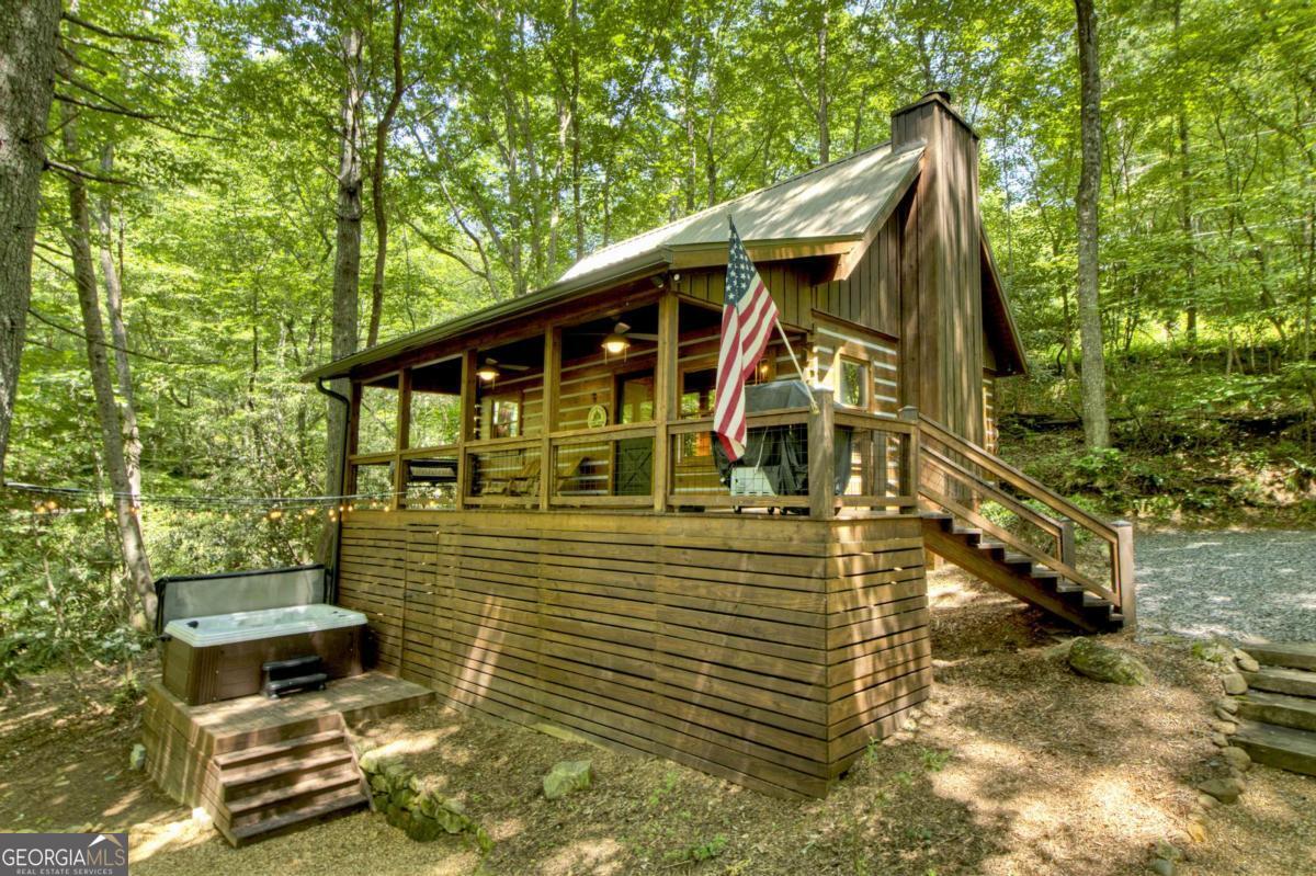 Escape to "STONE CREEK" a beautifully renovated cabin perched above the rushing waters of Fightingtown Creek-one of North Georgia's premier trout streams. Tucked away in a peaceful, wooded setting just minutes from downtown Blue Ridge, this charming 2-bedroom, 1-bath retreat offers the perfect blend of rustic charm and modern luxury. Step inside to discover a warm and inviting interior with thoughtful updates throughout. The fully remodeled kitchen features granite countertops, new appliances, and custom cabinetry, while the upgraded bathroom offers a spa-like feel with designer tile-work and contemporary fixtures. The living area boasts rustic mountain vibes with wood accents and a cozy fireplace, perfectly furnished to provide comfort and modern accents. Outdoors, relax in the private hot tub perched on the deck, where the sights and sounds of the creek provide the perfect backdrop. Whether you're sipping coffee at sunrise or enjoying a glass of wine under the stars, this setting is unmatched in its peaceful beauty. Offered fully furnished and completely turnkey, this cabin has a strong, established rental history, making it ideal as a vacation home, short-term rental investment, or your personal escape to the mountains. Don't miss this rare opportunity to own a creek front gem in the heart of Blue Ridge!