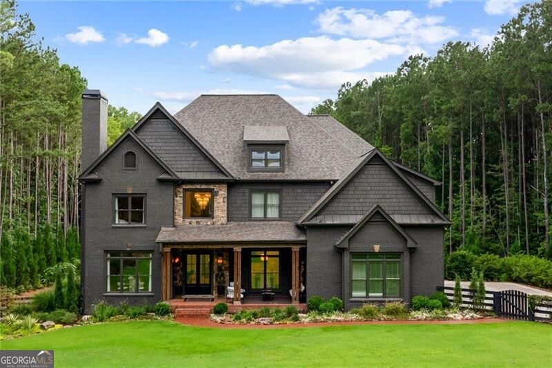 Tucked within a gated enclave and offering the rare blend of a sought-after Alpharetta address and low Cherokee County taxes, this stunning modern cottage-style estate is a true lifestyle property. Set on a beautifully landscaped lot with dual driveways, the exterior stuns new rock pathways, and a full yard transformation including a leveled, aerated backyard perfect for soccer play. Outdoor living is redefined with a heated saltwater pool featuring a blue light system, waterslide, and 10-person spa, paired with a round steel firepit, 18-speaker sound system with in-ground subwoofers, raised garden beds, firepits, and expansive patios for entertaining. Inside, the light-filled home features refinished Ashwood floors, fresh cedar accents, and over $100,000 in Restoration Hardware lighting. A Control4 smart home system integrates sound, lighting, hardwired cameras, and more. The open chef's kitchen is equipped with Sub-Zero, Wolf, and Miele appliances, plus double ovens and a walk-in pantry. Custom window treatments and built-in garage storage remain. The home boasts 7 total bedrooms, including a serene main-level primary suite with a gas fireplace. Upstairs offers four large bedrooms and the terrace level features two additional suites (one with separate entrance and kitchenette), a theatre, game room, and gym with sauna, all complemented by secondary laundry and ample storage. Experience elevated, turnkey living, just minutes from Milton and downtown Alpharetta.