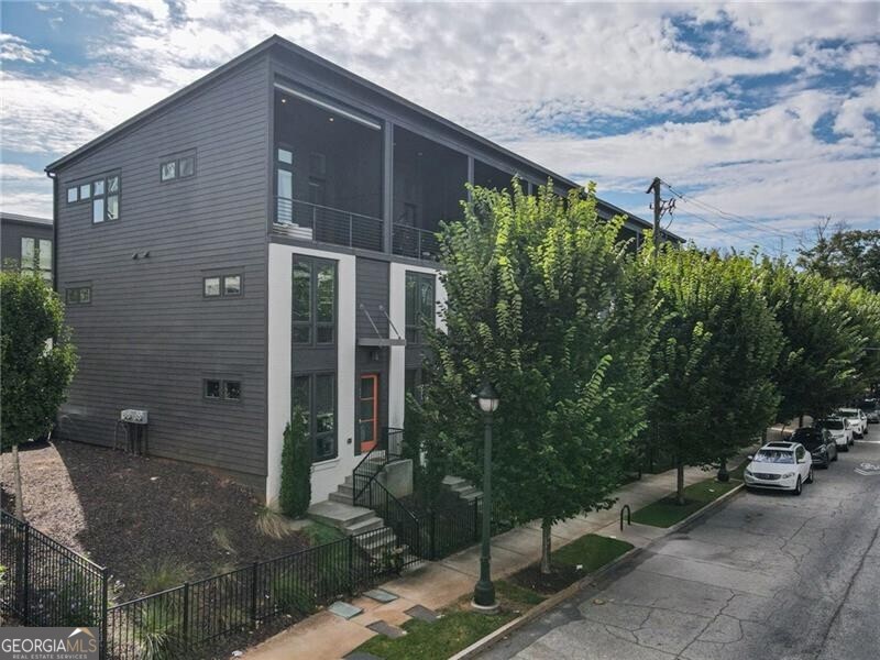 Experience contemporary city living at its best in this striking Atlanta townhome. Perfectly positioned in one of the city's most dynamic neighborhoods, Old Fourth Ward, this end unit blends modern design with everyday comfort and is flooded with natural light! The open-concept impresses with soaring ceilings, expansive floor-to-ceiling windows, and seamless connectivity between living, dining, and kitchen spaces. A generous quartz island anchors the chef's kitchen, complemented by sleek, high-end appliances-ideal for both entertaining and daily living. Step onto the covered balcony and take in sweeping skyline views as well as the greenery of surrounding trees, a rare pairing of urban vibrancy and natural calm. When the sun becomes too bright, easily lower the electronic shade to a level comfortable for you! Two spacious bedrooms each feature private baths, offering both privacy and convenience. A discreetly tucked-away laundry, behind barn doors, enhances the functionality of the space. The terrace level provides true versatility! The current homeowner has this space set up as a home gym, with custom cut gym flooring, and a Tonal Gym Machine. With upgraded fixtures throughout, ample storage, and a garage with an EV charger, this home balances style with substance. Beyond the front door, you're minutes from Atlanta's best-Ponce City Market, the Beltline, Old Fourth Ward, and Piedmont Park-all within effortless reach. This is a townhome that delivers sophistication, livability, and location in equal measure.