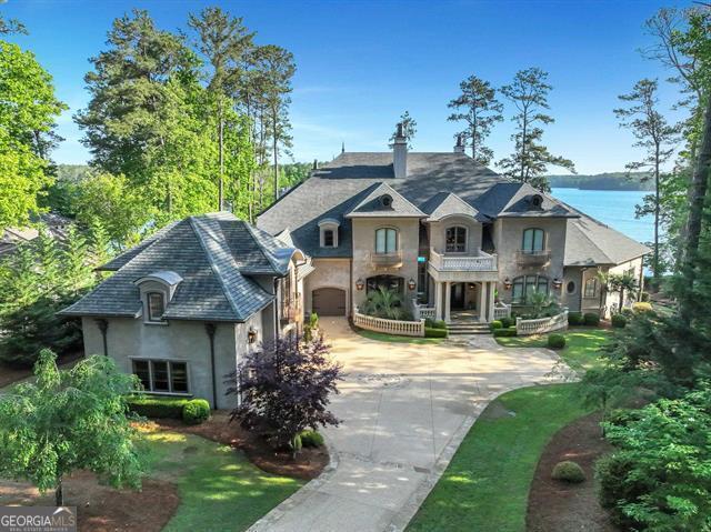 Embrace a Luxurious Lakefront Lifestyle in this Exquisite Resort-Style Estate. Positioned to offer an unparalleled lifestyle within the prestigious Reynolds Lake Oconee community. This gorgeous home was custom-built in 2018 by Dream Built Homes and affords breathtaking open-water vistas, ensuring every moment at home feels like a vacation. This turnkey property comes fully furnished with interiors curated by Black Sheep Interiors, ensuring that every detail has been meticulously considered for sophisticated living. Situated amidst 6 championship golf courses, with access to the renowned Ritz Carlton and Reynolds amenities, this property is a haven for those who aspire to live a life of luxury and leisure. As you step into the expansive great hall of this residence, you are greeted by soaring vaulted ceilings and sweeping views of the lake through massive rolling glass doors. These doors open to your Lanai, extending the living space into 2,500+ square feet of opulent outdoor living and entertaining areas. The seamless integration of indoor and outdoor spaces epitomizes upscale lake living. The outdoor experience is highlighted by a dramatic saltwater infinity pool, strategically positioned on the main level for optimal convenience and views. This exquisite pool area is complemented by a fully equipped outdoor kitchen featuring a Wolf grill and Primo smoker, bar seating, and a spacious dining area. The home itself does not shy away from luxury, boasting seven elegantly appointed suites including a master and additional suite on the main level, four on the upper level, and a complete carriage apartment, catering to both privacy and lavishness. The main level is adorned with Italian travertine floors and ceilings over 12 feet high, creating an open, airy feel throughout. The chef's kitchen is a culinary dream with double quartzite islands, Sub-Zero and Wolf appliances, dual dishwashers, and double refrigerators, all complemented by a separate breakfast room offering panoramic lake views. Additional amenities include a centralized wine room with ample storage, a dedicated catering area, and direct elevator access to the upper level where entertainment options abound. Enjoy a private theater that seats 12, a retro blue bar with lounge seating, and a full gym with a sauna.  This property is more than just a home; it's a lifestyle promise, set in one of the most coveted environments with every possible luxury at your fingertips.