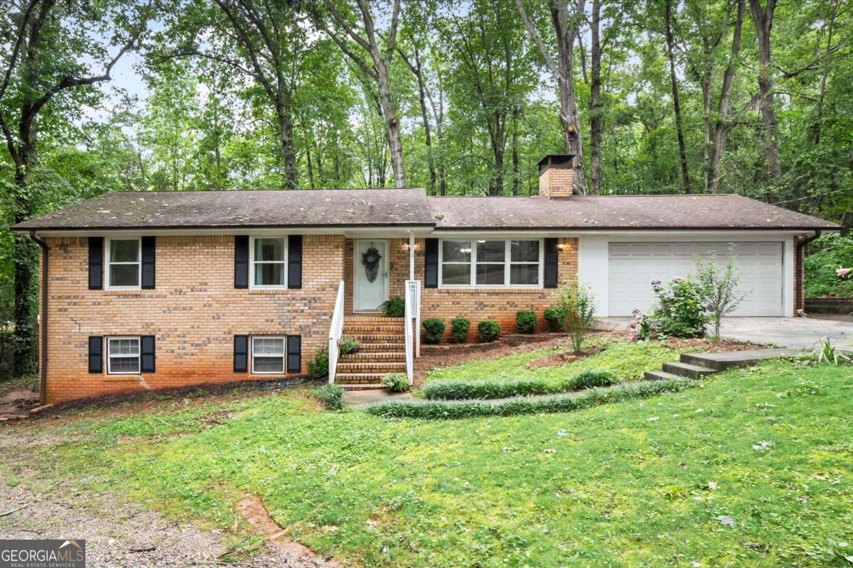 Charming 4 Side Brick Ranch nestled on a beautiful, wooded lot in a quiet Cumming neighborhood just .3 miles from Cumming City Center. Nestled up to a 20+ acre Conservation Tract, the property provides exceptional privacy and the feel of country living while still being in the heart of town. Recently updated with new granite countertops, new oven, new water heater, new master vanity & light fixtures, all new interior doors, new lighting, fresh paint, and new carpet throughout the main level. The full basement features a side daylight private entrance offering a recently remodeled income-generating 1 bedroom/1 bath apartment with a full kitchen, LVP flooring throughout, and private laundry access. The basement also hosts a workshop/storage area and an unfinished family room with a brick fireplace, with potential to finish an additional 500+ living space. Enjoy the large fenced-in backyard while relaxing on the screened-in porch and enjoying the abundant natural light from the many windows. Plenty of parking with a recently enclosed two-car garage, oversized driveway, and gravel drive to lower-level apartment. With no rental restrictions, this property presents an excellent opportunity for investors in a highly sought-after location for two potential rentals in one property. With a welcoming front yard and thoughtful updates, this home is priced to sell-don't miss your opportunity!