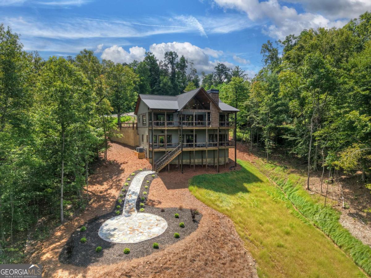 Located less than five minutes from vibrant downtown Blue Ridge, this newly constructed home in the prestigious gated community of Staurolite Mountain blends rustic charm with refined comfort. Thoughtfully designed with high-end finishes throughout, the home welcomes you with warm wood accents, an open floor plan, and abundant natural light. The heart of the home features a striking double-sided fireplace, creating a cozy ambiance for both the great room and dining area. The gourmet kitchen boasts custom cabinetry, premium appliances and a butler's pantry for added convenience. Each spacious bedroom offers an en suite bath, providing privacy and luxury for family and guests. Spa-like features throughout including a steam shower, double vanities and a large soaking tub are sure to impress. Outdoor living is just as inviting, with a beautifully designed hardscape patio and fire pit perfect for entertaining or relaxing under the stars. Set in a sought-after community with paved roads and gated access, this mountain retreat combines modern comfort, rustic elegance, and an unbeatable location close to shops, dining, and outdoor adventure.