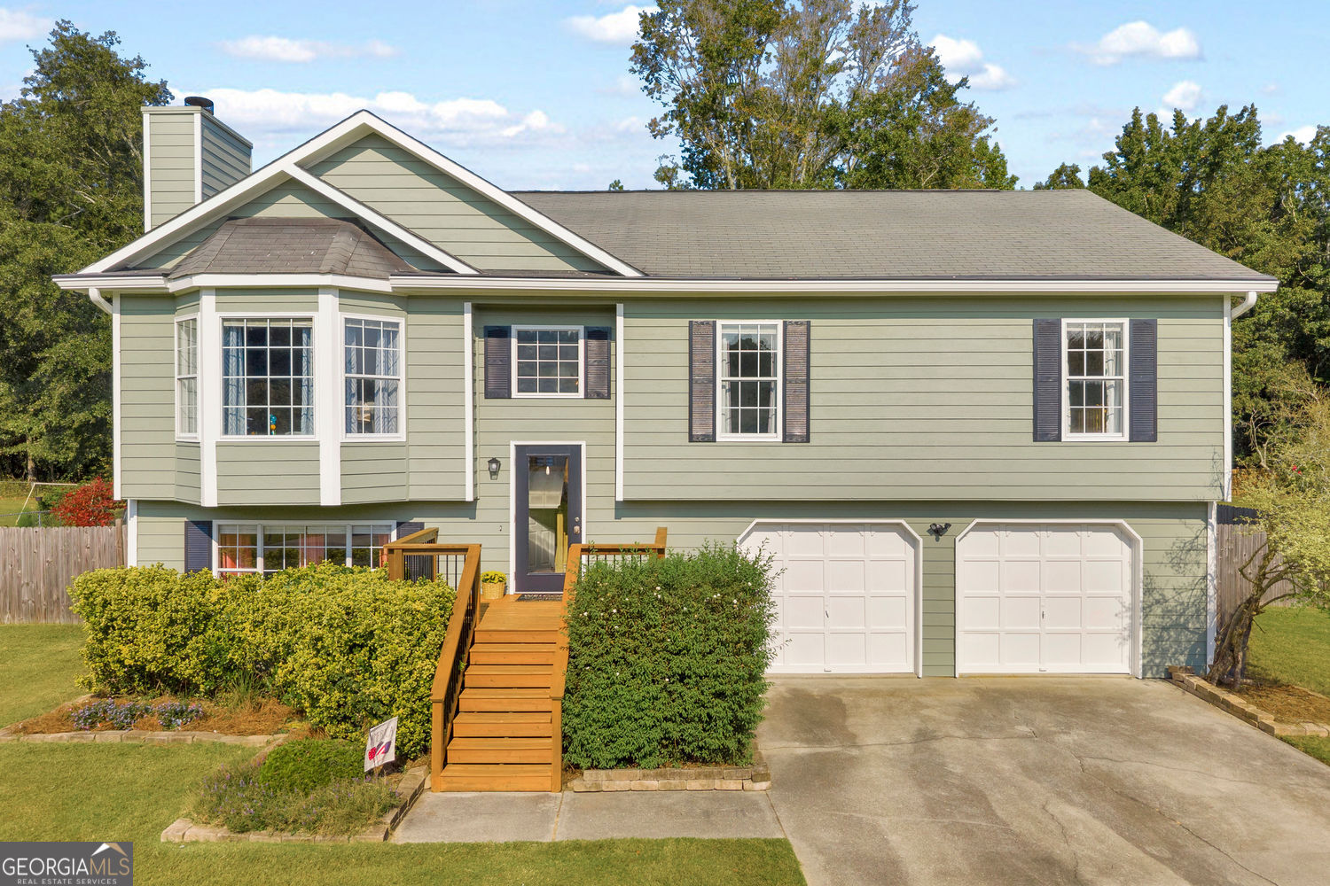Tucked in a quiet neighborhood on nearly half an acre, this home offers the perfect blend of space, comfort, and modern updates, all within the sought-after Mill Creek Schools cluster. The large, level fenced backyard is perfect for entertaining, with plenty of room to play or gather around the recently added fire pit. A newer back deck with fresh stain and vaulted screened porch create inviting spaces to relax and unwind outdoors year-round. Inside, the vaulted main living area feels bright and open, featuring updated kitchen counters and backsplash, a large butcher block island, stainless steel appliances, and a layout that flows seamlessly into the family room and dining room for true open-concept living. The primary suite offers a generous bedroom and a tasteful sliding barn door leading to the updated bath with double vanities and a large walk-in shower. The secondary bath has also been beautifully updated, and laundry is conveniently located on the main level. The basement provides even more living space with a large bonus room, fourth bedroom, and an oversized 2-car garage with storage space and possibly room for an additional small vehicle. Fresh exterior paint ensures great curb appeal, while the thoughtful updates throughout make this home move-in ready. Conveniently located near shopping, dining, parks, Lake Lanier, and I-85. This one is a must-see!
