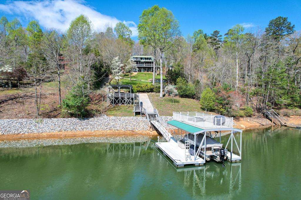 Deep water & stunning vistas at every turn. This unique lakefront home offers a beautiful blend of luxury and natural beauty. With three bedrooms, three full baths, and two half baths, it provides ample space for comfort and relaxation. The large drive-through garage-complete with a full bath-adds convenience and versatility. Step outside and you're greeted by a two-story boat dock, a fenced yard with a hot tub, and a cozy fire pit-perfect for lakeside gatherings. The fully finished basement offers added living space and the potential for a fourth bedroom, while the spacious kitchen and living room serve as ideal entertaining areas, boasting panoramic views of the lake and breathtaking mountain vistas. A detached garage includes a fourth full bathroom, and there is generous storage throughout the property. For those seeking a move-in-ready retreat, select furnishings and the boat lift are negotiable, adding even more value and convenience to this exceptional lakefront lifestyle.