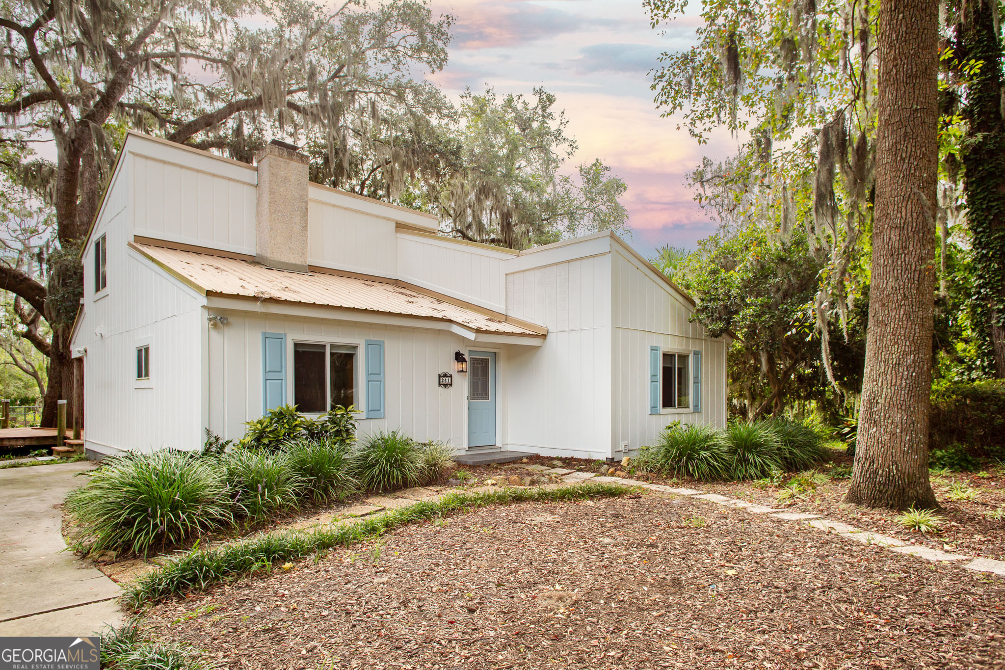 There's something special about this spot on Satilla Drive. The home itself has just under 1,900 square feet with 4 bedrooms and 2 baths, but numbers don't tell the whole story. What really makes it stand out is the way it's tucked beneath old oaks draped in Spanish moss, with wide views of the marsh stretching out behind it. Inside, the vaulted great room is anchored by a floor to ceiling tabby shell fireplace - the kind of feature that feels both timeless and unique to coastal Georgia. The kitchen window overlooks the peaceful backyard and out to the marsh, so whether you're cooking dinner or sipping coffee, you're always connected to the view. Down the hall you'll find a full bath and bedroom along with a flex space that can be used for another bedroom or living area. Make your way upstairs to find two more bedrooms and another bathroom. Step outside and it gets even better. The wraparound deck gives you front row seats to sunrises and coastal breezes. The yard has the feel of an old garden - mature plantings, winding paths, and a giant oak that anchors the whole space (rope swing included). The owners have been thoughtful about updates, too. Within the last year, they've replaced the HVAC system and water heater, had the chimney cleaned and certified, and added custom remote controlled blinds for convenience. An irrigation system keeps the nearly half acre yard lush and healthy. The combination of modern updates and maintenance means you can settle in without a long to-do list. It's not a cookie cutter house, and that's the point. This is a place for someone who wants a little character, a little privacy, and a daily reminder of what's beautiful about living on the Georgia coast.