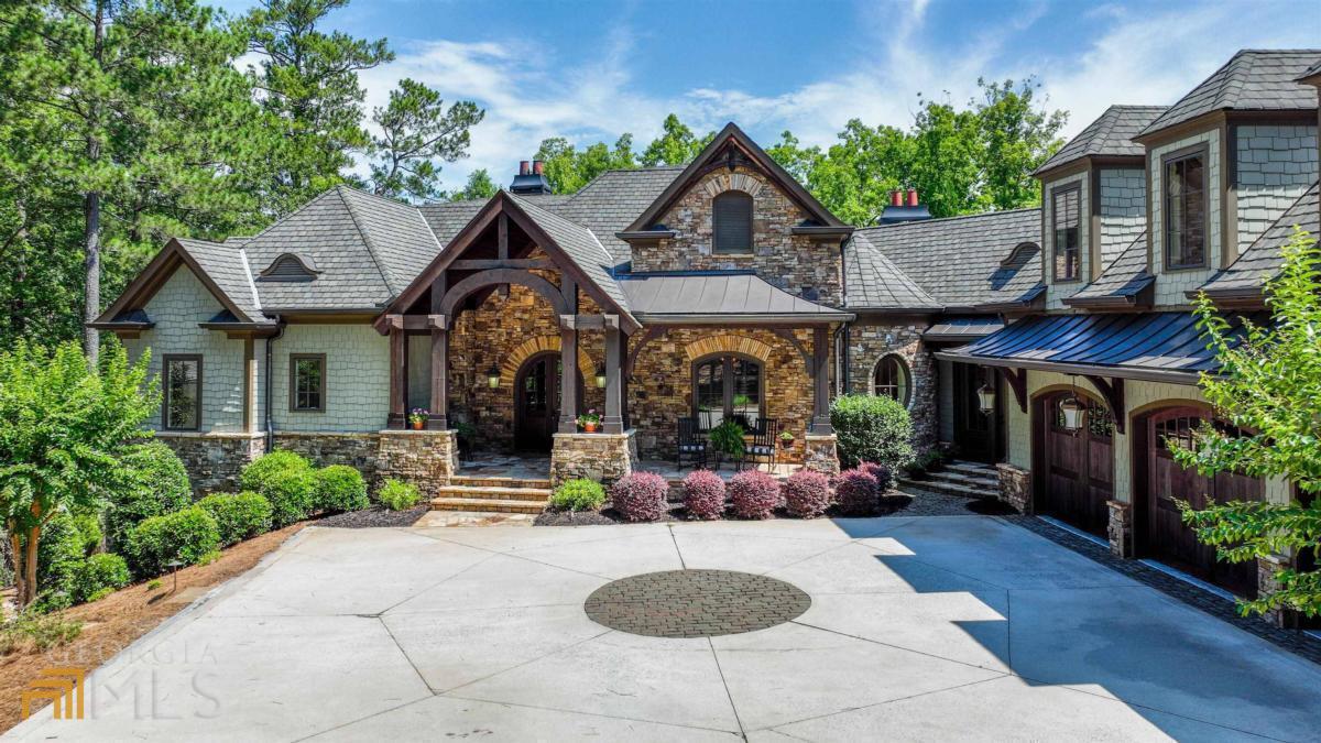 CLASSIC, BEAUTIFUL WATERFRONT HOME AT REYNOLDS LAKE OCONEE! GORGEOUS, QUALITY CRAFTSMAN STYLE 6,500+ SQ FT NESTLED ON A PRIVATE LOT, STEPS FROM THE LAKE AND YOUR PRIVATE BOAT DOCK. Your family summer lake home awaits, featuring a beautifully landscaped backyard with a pool, spa, outdoor kitchen and expansive stone patio. Stunning front porch with wood beams and interiors that showcase fine workmanship and custom details will impress you. Natural stone accents and mill work, open floor plan with rich wood details balanced with neutral tones, brick barrel ceiling, custom built-ins, this is one of the most well-constructed lake homes at Lake Oconee. The natural stone spiral staircase is a showstopper and welcomes you into the stunning foyer, onto the spacious great room with stone fireplace, wood beams and glass doors highlighting the fabulous lake views. The gorgeous dining room with brick barrel ceiling and accents is adjacent to the recently updated kitchen that features a stone surround cooktop, double ovens with warming drawer, large refrigerator, 2 dishwashers, microwave drawer, custom cabinetry and a large center island. Enjoy the porch off the kitchen with a fireplace and fantastic views of the lake and serene backyard. The luxurious master suite on the main level features a sunroom and a fireplace. Large master bath offers heated tile flooring, his and her custom closets, separate vanities, soaking tub, and walk-in shower. The spacious garage suite features a living area or an office, and two bedrooms with a full bath and steam shower. The terrace level boasts large game or billiard room, family room, custom full bar, wine cellar and three en-suite guest bedrooms. Walk out to the incredible backyard made for entertaining with an expansive covered stone patio, pool, hot tub, outdoor kitchen and outdoor dining area. It is rare to find a lake property that provides ultimate privacy and the convenience of being steps away from the water and your own private boat dock. The home is located within boating minutes to the Ritz Carlton, Lake Club, jumping rock, and other lake amenities. Easy access to Reynolds Lake Oconee's most scenic walking trail is a big plus. It is also conveniently located within minutes of driving distance to the main entrance of the community. This immaculate lake home is move-in ready for you and your family to enjoy. Membership is available.