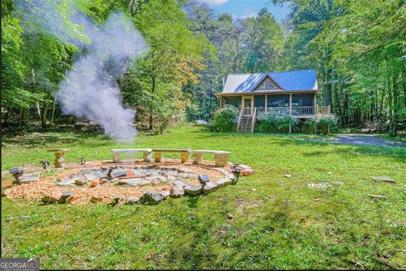 Escape to the mountains with this charming cabin retreat set on 2.5 private acres! Featuring beautiful pine floors and walls throughout, this home offers the warmth and character you've been looking for. Enjoy your morning coffee on the large screened front porch while watching wildlife in the peaceful surroundings. The updated kitchen opens to a cozy family room with vaulted ceilings and a woodburning stove-perfect for cool mountain evenings. The main level includes a bedroom and full bath with laundry, while upstairs offers a loft, second bedroom, and additional full bath. Step out back to relax under the stars in the new hot tub on the private deck. Whether you're seeking a serene getaway or a high-performing short-term rental, this mountain retreat checks all the boxes.