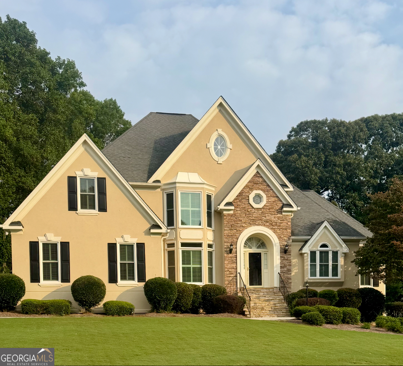Welcome to this meticulously maintained two-story home on a full finished terrace, currently undergoing major improvements, giving the future owner the chance to enjoy a beautifully updated property located in one of Grayson's most desirable and well-respected communities. Offering a perfect blend of comfort, elegance, and functionality, with just a minutes walk to the resort-style amenities including a clubhouse, lap pool, four lighted tennis courts, pickleball courts, two fishing lakes with picnic areas, and more. Conveniently located near major highways for an easy commute, within an excellent school system, and close to healthcare, shopping, dining, and year-round entertainment. From the moment you arrive, you'll be impressed by the stacked stone accents, flagstone front stoop, and professionally landscaped grounds. A spacious driveway leads to the side-facing two-car garage, providing both functionality and curb appeal. Step inside the two-story foyer, where wainscoting, hardwood floors, and plantation shutters set a tone of timeless elegance. Off the foyer, you'll find a formal dining room and a formal living room that also makes an ideal home office. The vaulted family room is the heart of the home, featuring a wall of windows that flood the space with natural light, a cozy fireplace, and an overhead catwalk. An adjoining built-in bar area seamlessly connects to the eat-in kitchen, creating a perfect flow for entertaining. The kitchen boasts a center island, double oven, large custom pantry with excellent storage, and direct access to the deck. The laundry room is equally impressive with cabinets, a sink, and folding table, keeping everything organized and efficient. The oversized primary suite on the main level is complete with double tray ceilings, private deck access, and French doors leading to an en-suite bath featuring split double vanities, jetted tub, walk-in shower, and dual walk-in closets. Upstairs, three spacious secondary bedrooms include an en-suite in addition to a Jack and Jill bath, providing privacy and convenience for family or guests. The finished terrace level offers endless possibilities to customize this level to your lifestyle with a bonus room, built-ins, second fireplace, wet bar, full bathroom, and two potential bedrooms. This versatile space is perfect for multi-generational living, a media room, billiards, or a home gym. There's even an attached workshop with pegboard walls for all your projects and hobbies. Outside, enjoy a sprawling level backyard with wooded views and stairs to easily access the main level deck. The entire yard, front and back, is irrigated for low-maintenance landscaping. This remarkable home offers a rare combination of luxury, space, and location, making it a must-see for anyone seeking an elevated lifestyle in the heart of Grayson.