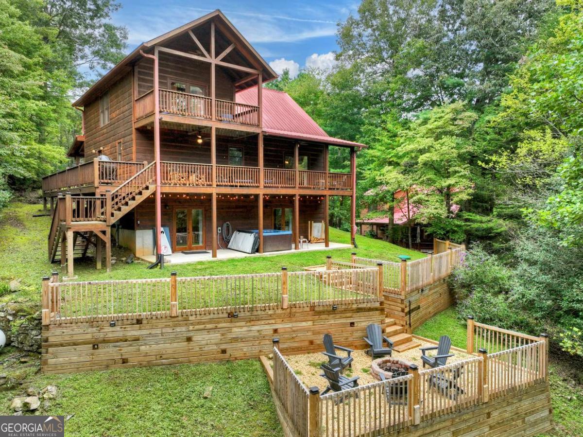 Nestled on a private 2.45-acre lot just six miles from the charm of downtown Ellijay, this beautifully remodeled cabin offers the perfect blend of rustic charm and modern comfort. Step inside to the great room with its soaring cathedral ceiling and a magnificent stone fireplace, creating a warm and inviting atmosphere for family and friends. The open-concept layout connects the great room, dining area, and kitchen, making it ideal for informal gatherings. The recently finished basement is a fantastic bonus, featuring a spacious game room, a third bedroom, a bunkroom, and a full bath, providing ample space for guests or a growing family. Outdoor living is a dream here, with covered decks on two levels and a terraced backyard complete with a fire pit area-the perfect spot to unwind and enjoy the seasonal mountain views. The large upstairs master suite is a private sanctuary, boasting a vaulted ceiling, a private balcony for morning coffee, and a luxurious en-suite bathroom. This cabin isn't just a home; it's a lifestyle.