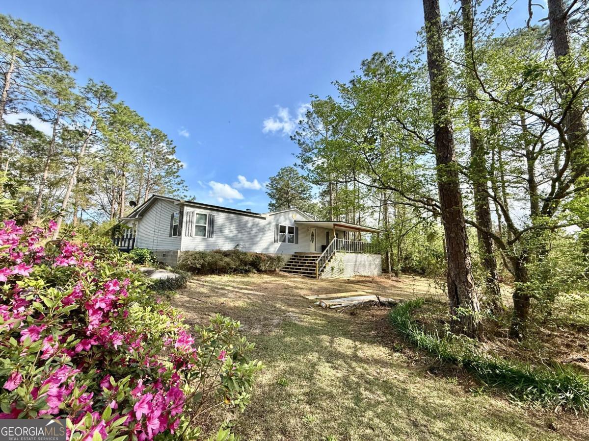 As you enter the paved driveway you will catch a glimpse of all the unbelievable extras this home on 3 acres provides. The home offers 3 bedroom 2 bath with a spacious add on sunroom/game room, a nice porch on the front. A 20x30 barn adds space for equipment, storage, or a workshop. There is also a multi functional building which has back storage, side open canopy, front storage an area with a sink, 3 sided area to work with an attached greenhouse this building alone has so many uses. A shed completes the out buildings. There is an established orchard including plums, apples, and satsuma. If growing your own vegetables is on your list there is an area ready for that. Packed with so much this package has something to surely please everyone. Call list agent Vickie Bateman 912-253-0268.