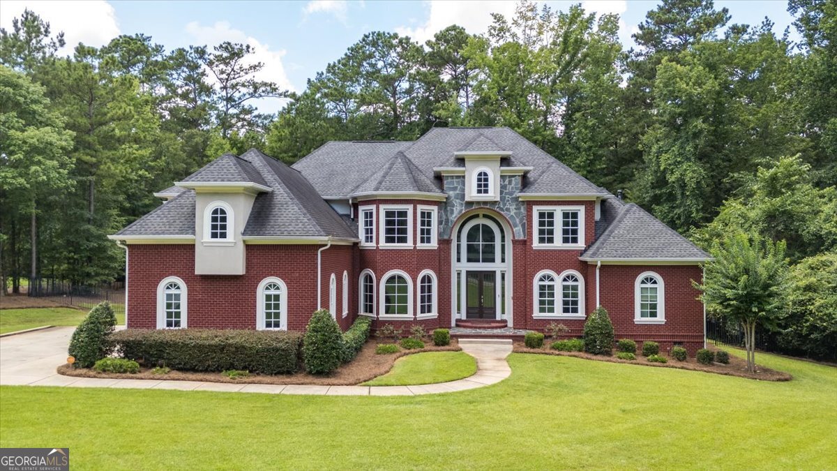 Charming spacious and designed for elegant living. This beautiful home is within an exclusive gated community in Macon Middle Georgia. Sitting on one-plus acre lot, the property enjoys beautiful maintained landscaped yards with a private wrought iron fenced backyard a gorgeous inground pool, covered pavilion, perfect for entertaining or quiet retreats. The floor plan is ideal for growing families or those seeking luxurious amenities. The main level includes the fireplace primary bedroom suite with private access to the rear deck and covers the full space of the right side of the main level, a second bedroom with it's private bath and views of the spacious backyard, an office, an awesome two-story foyer giving views of a dual staircase entrance, two-story fireplace sitting room, formal dining room, cathedral ceiling fireplace gathering room adjacent to the wide open kitchen with its semi-circular built-in eating bar, built-in desk, top of the line appliances, double oven and wide kitchen island. The upstairs features four bedrooms (one privately located bedroom with it's private bath), three full baths, a second office, media room with wet bar a hallway with open views of the foyer, gathering room and living room. This elegant home features beautiful architectural details; soaring ceilings, elegant built-in wall recessed display spaces, gorgeous and exaggerated window heights. Additional features includes a three-car garage, quick access to eateries, I-475 and I-75. This lovely home awaits you!