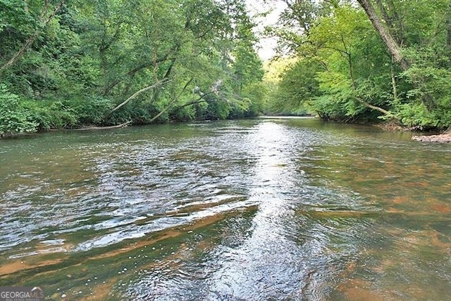 PRICE IMPROVEMENT - THE FANTASTIC ETOWAH RIVER TUNNEL, 191+/- acres, and a Country Mile of river along and through the property!! The only gold mining Tunnel of its kind in the entire United States with a river flowing through it - a historic remnant from the gold rush heydays of Dahlonega, GA. Begun in the late 1800's and completed in the early 1900's, the 9' diameter Tunnel was blasted perpendicular through some one thousand feet of solid Georgia granite and the entire river was subsequently diverted through, short-crossing nearly a mile of previous looping river course. The newly exposed dry river bottom was then mined down to the bedrock for the precious yellow gold it contained. A decade later the Etowah is free again to flow around its original course but a portion still gushes strong through the Tunnel on this property. The location of this tract in Dahlonega's Gold Belt gives a significant historical background unique in the United States where millions of dollars' worth of gold was extracted from this area of Georgia's gold deposits. Many exceptional scenic amenities are here to enjoy and over a mile of the Etowah River winds through and along the property from shoal-noisy to strong and swirling. Acres of flat grassy and alternately shaded fields run along and just above the entire length of the waterway to make this a very family-friendly waterfront property. Collected along the riverbanks are towering cliffs of granite and exposed boulders; mountain laurel, rhododendron, and doghobble line the water's edge and put on showy blooms in the Spring. Clear Creek and Buck Creek also flow through and there are three spring-fed ponds on the property plus a small impoundment. Open grassy carpets of gentle terrain welcome in rays of sunshine and pretty timber covers the property with protection and shade. Scenic vistas and meadows along the upper plateau provide an open feel and the main line of the Blue Ridge Mountains can be seen in the distance. The tract is totally private and secluded and protected by heavy wrought-iron gates protect the access roadways yet the property is very convenient to Hwy 400 and only ten minutes or so from major shopping, dining, and activities. A system of groomed roadways traverse the property providing easy access to all points of the land and up by the main pond there's a shop building with storage. Historic Dahlonega, its wineries on The Dahlonega Plateau and the Chattahoochee National Forest are but a few minutes up the road. Dawsonville along with about every urban amenity you can think of is just a few minutes south and Atlanta is forty minutes away yet a world removed. This tract offers potential for many uses - the location and layout would excel as a private mountain retreat with all the appeal and amenities of the Southern Appalachian Mountains. Or perhaps for a unique development or venue. Or simply for personal enjoyment, investment, and adventure. This is certainly one of the most outstanding and compelling river properties in the South with a heritage unique across the Nation. Offers Encouraged!
