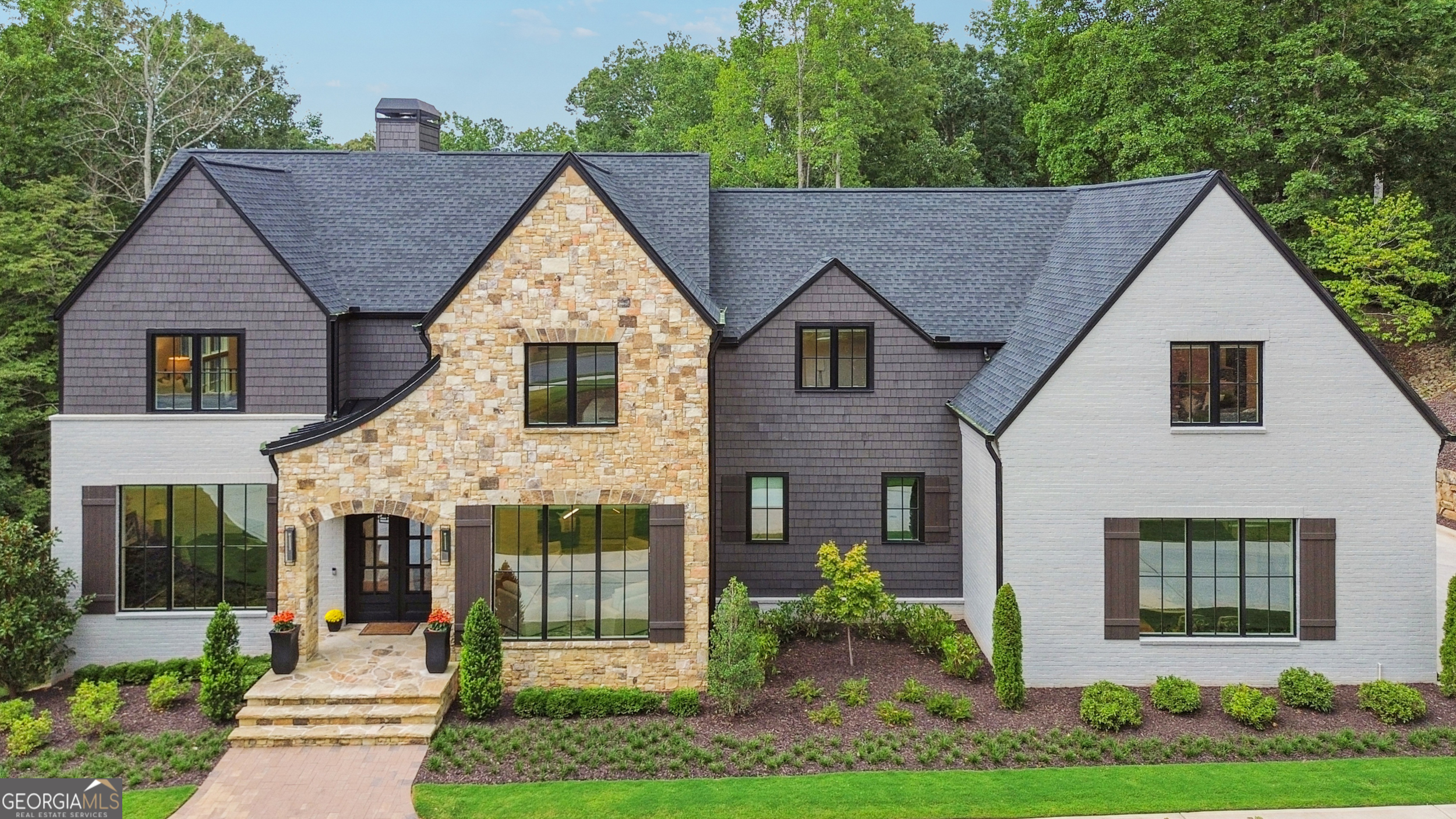 Discover this stunning, 2023-built modern craftsman home, perfectly situated on a cul-de-sac in the highly sought-after Litchfield Hundred community. Resting on 2.1+ private, wooded acres, this residence offers a tranquil retreat while keeping you close to vibrant city amenities (swim, tennis, and pickleball) and some of North Fulton's prestigious private and public schools. Centrally located near Crabapple, Milton, Roswell, and Alpharetta, it blends peaceful living with unmatched convenience. Step inside to expansive open-concept living, where the family room flows seamlessly into the eat-in kitchen. Towering floor-to-ceiling windows along the back of the home frame breathtaking wooded views, filling the interior with natural light. The kitchen is a showpiece-white oak cabinetry, quartz countertops, a hidden walk-in pantry, and top-of-the-line Thermador stainless appliances including a 48" range, pot filler, and appliance garage. A mudroom with built-in shelving adds everyday convenience, and the covered back deck is the perfect place to relax or entertain while overlooking the level backyard, ideal for outdoor living and with plenty of space to add a pool. The primary suite is located on the main level, offering peaceful views-even from the spa-like primary bathroom. Upstairs, you'll find all four secondary bedrooms, each with its own private ensuite bath, including one oversized suite with a dry bar. Additional highlights include white oak floors, two laundry rooms (main and upper levels), and a three-car garage. The full, unfinished basement-with soaring 14+ ft ceilings and a bathroom stub-offers endless possibilities for a basketball court, golf simulator, theater, additional suite, or any custom vision you can imagine. This home perfectly blends architectural beauty, modern luxury, and an idyllic 2.1+ acre setting in one of the area's premier neighborhoods.