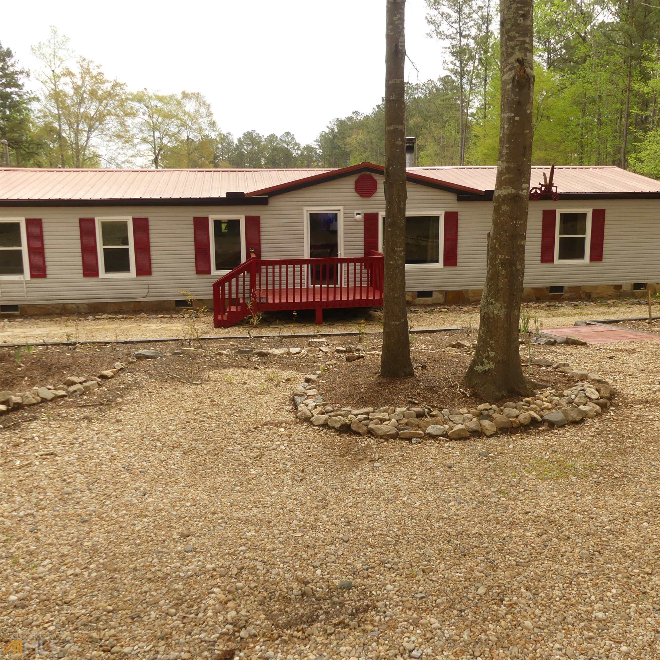 Welcome home. 3.6 acre home with an established vineyard. 30 plus blueberries, 20 plus peachtrees, muscadines vines, apple trees, fig trees, pomegranates. Fenced yard for privacy and pets. Parking shed for tractor, a storage building, and a man cave that will not wait complete with water and power a place to be alone away from it all. This property has a back porch that extends the full length of the home that leads down to the above-ground pool with a huge deck full surrounding. Drive is covered with river rock. Landscaped with timbers and foundation veneered with stone. A new black gutter system and new soffit trim make for an attractive easy maintained exterior. The Interior has a unique design with metal ceilings, laminate floors, and a wood-burning stove. Sitting in a much-desired neighborhood within walking distance of school and firehouse, enjoy the comfort of peace, quiet, and security. The family has enjoyed this home but are relocating to their home state, a must-see for a qualified buyer with a heart for the country.
