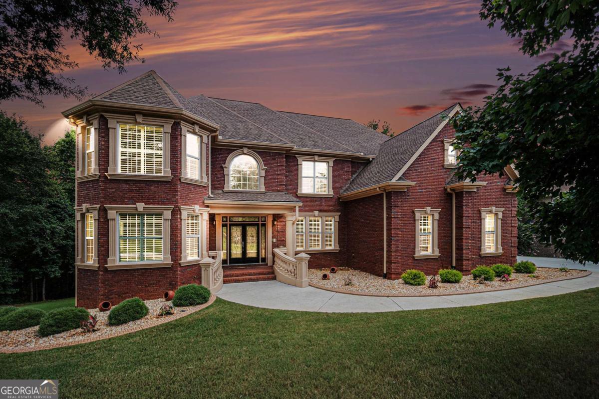 Welcome to room-for-everyone living in prestigious Madison Creek! This elegant, custom all-brick estate rests on a rare 1.78-acre wooded homesite and delivers the space, flexibility, and privacy today's buyers crave. A graceful approach leads to a dramatic two-story foyer opening to oversized formal and family spaces framed by rich millwork, soaring ceilings, and classic crown/dentil molding that speak to true craftsmanship. The gourmet kitchen anchors the main level with granite countertops, center island, double ovens, stainless-steel appliances (refrigerator stays), abundant cabinetry, and a bright breakfast area that flows to a large entertaining deck overlooking serene, treed grounds-perfect for gatherings. Three fully finished levels create outstanding multi-generational options, guest/in-law living, or potential rental income. Total of 8 bedrooms and 5 full baths across the home. All-brick construction, double rear decks, side-entry 3-car garage, and generous outdoor play/garden space set this property apart in Rockdale County. Terrace (lower) level: 3 bedrooms, full bath, fresh paint, carpet, kitchenette, laundry room, abundant storage, theatre/media room, and utility space with tankless water heaters-ideal for long-term guests or an income suite. Main level: hardwood floors; tiled baths; fresh paint; formal dining & formal living; fireside family room; main level en-suite bedroom/bath for aging in place; smart Nest thermostat; Vivint security system & cameras remain. Upstairs: enter from kitchen or main foyer stair. Hardwood on stairs; luxury vinyl in bedrooms; tiled baths; 4 bedrooms/3 baths including a generous primary retreat with private sitting room, convenience refrigerator, access to an upper deck, large walk-in closet, and oversized shower. Upstairs laundry. Recent service/maintenance notes (per seller): New roof installed in 2022; Move-in ready with room to personalize. Ready for space and flexibility on acreage in Conyers? Schedule your showing today!