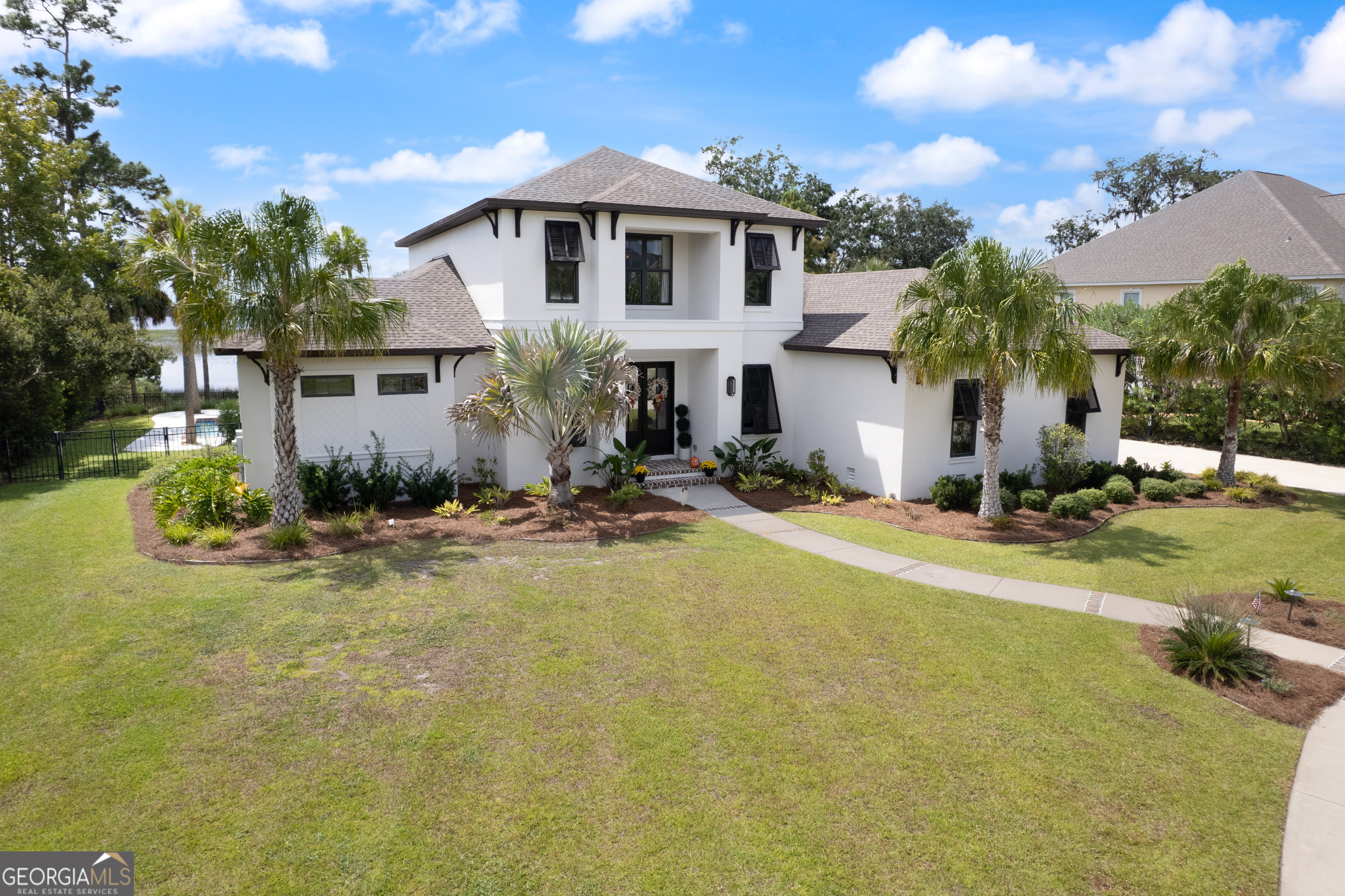 Everyday life comes with true million-dollar views. In coveted Oak Grove Island Plantation, this custom home blends refined finishes with marsh-to-river vistas that shift with the light-sunrise, moonrise, and golden hour on full display from the main living spaces. An airy, open layout frames the water the moment you enter. Tall ceilings, expansive windows, and thoughtful millwork create a calm, upscale backdrop as the great room flows to dining and a chef's kitchen with quality cabinetry, abundant prep space, and an oversized island that naturally becomes the social hub. The privately positioned primary suite is a retreat with a wall of glass to the water and a spa-style bath featuring a walk-in shower, soaking tub, dual vanities, and custom his-and-hers closets. Secondary bedrooms and flexible spaces (office, fitness, guest) provide comfort and privacy, while quiet upgrades-solid-surface finishes, designer lighting, and smart storage-show up where they matter most. Outdoor living shines: a covered terrace captures the panorama, and a sparkling pool sets the stage for afternoon swims and sunset gatherings. Beauty meets performance with dual HVAC for zoned comfort and triple spray-foam insulation for efficiency; per the seller, average power bills are ~$200/month-remarkable for a home of this caliber. A comprehensive security system adds peace of mind for full-time living or an easy lock-and-leave coastal escape. Minutes from daily conveniences and an easy hop to St. Simons and Jekyll Island beaches, marinas, dining, and I-95, Riverwalk delivers that rare blend of nature, privacy, and convenience-close to everything, yet a world apart. If you're seeking a custom home that lives comfortably and showcases the coastal landscape like art, this is it.